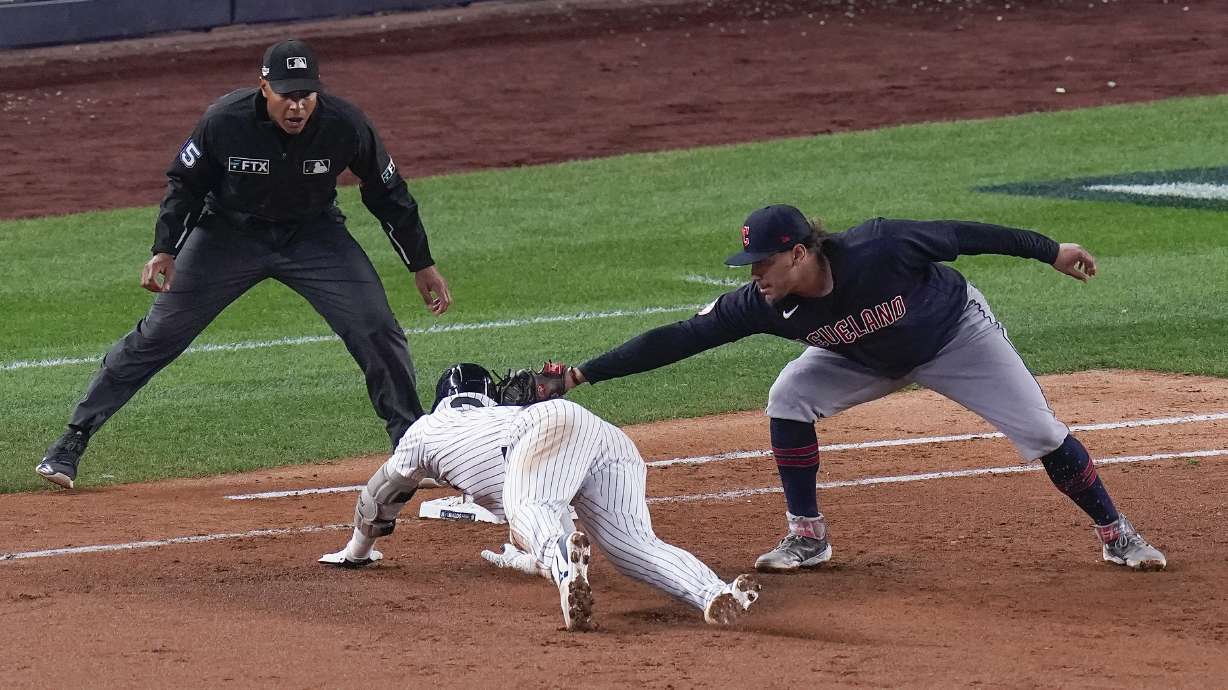 New York Yankees Josh Donaldson is tagged out by Cleveland Guardians first baseman Josh Naylor as he tries to get back to the first base bag after hitting a single off the right field wall during the fifth inning of Game 1 of an American League Division baseball series, Tuesday, Oct. 11, 2022, in New York.