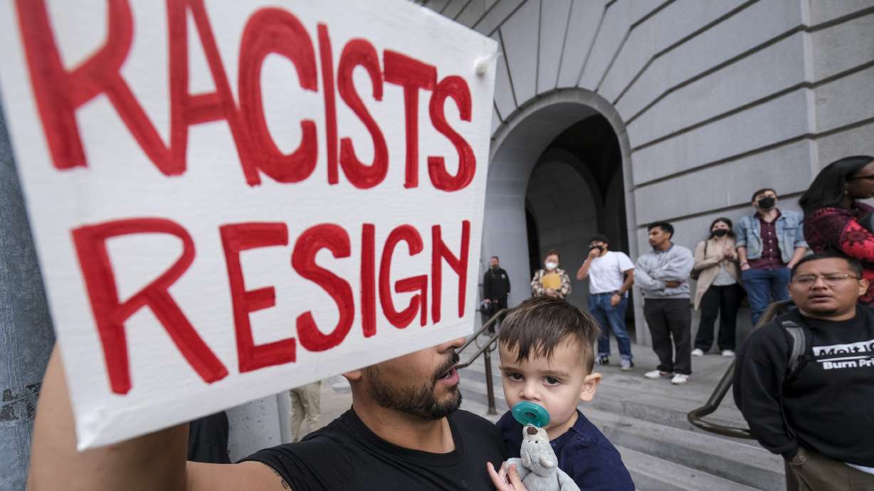 Shervin Aazami holding his son Barrett and a sign protest outside City Hall during the Los Angeles City Council meeting Tuesday in Los Angeles. Former Council President Nury Martinez has announced that she is resigning her council seat.