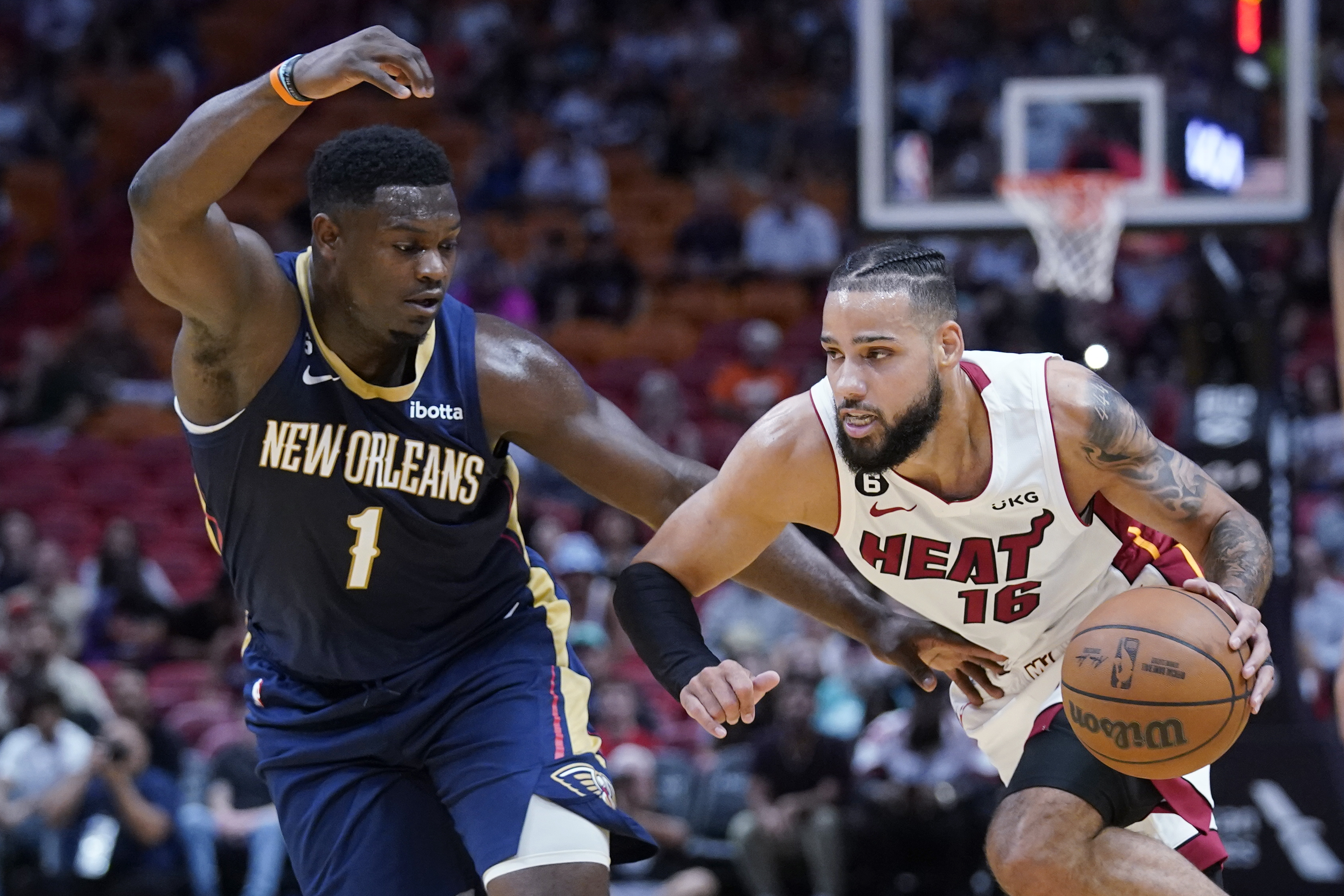 Miami Heat forward Caleb Martin (16) drives past New Orleans Pelicans forward Zion Williamson (1) during the first half of a preseason NBA basketball game, Wednesday, Oct. 12, 2022, in Miami.