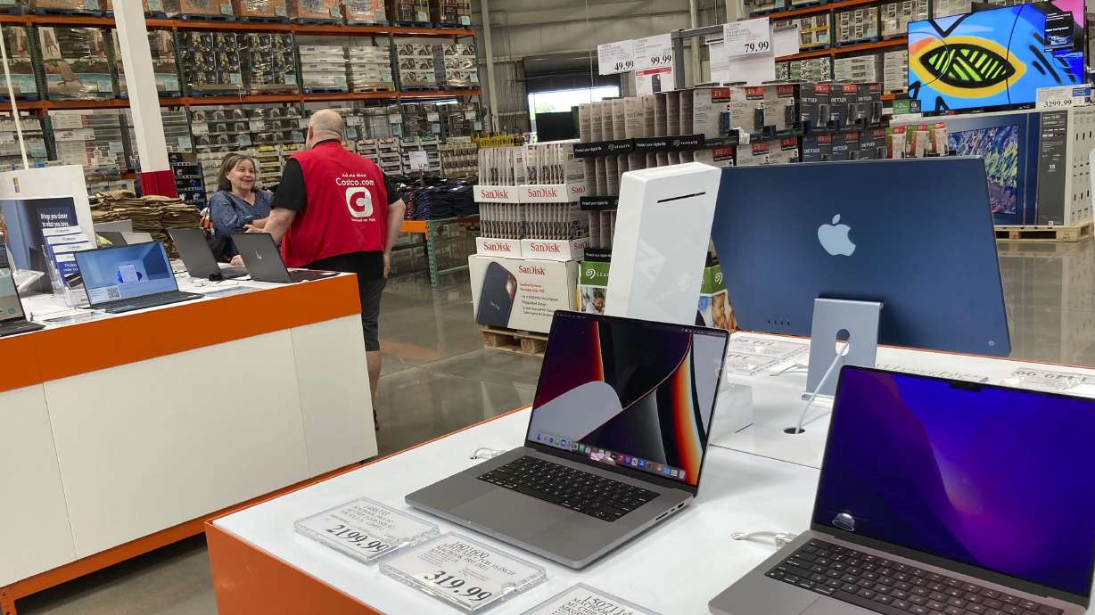A sales associate helps a prospective customer as laptops sit on display in a Costco warehouse, Aug. 15, 2022, in Sheridan, Colo. The U.S. retail sales rose an unexpected 0.3% last month, from being down 0.4% in July, the Commerce Department said Friday.