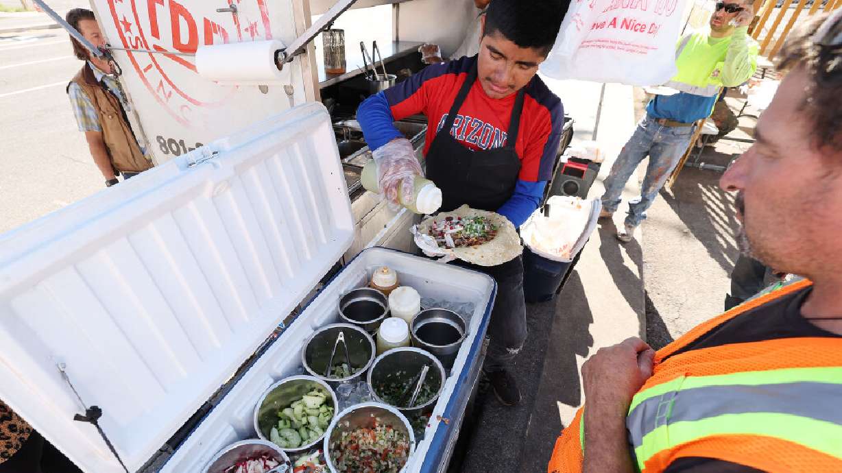 Lorenzo Lopez adds condiments to a customer's tacos at Tacos Don Rafa taco cart near the former Sears building on State Street in Salt Lake City on Friday. Intermountain Healthcare is planning to raze the building and develop the property.