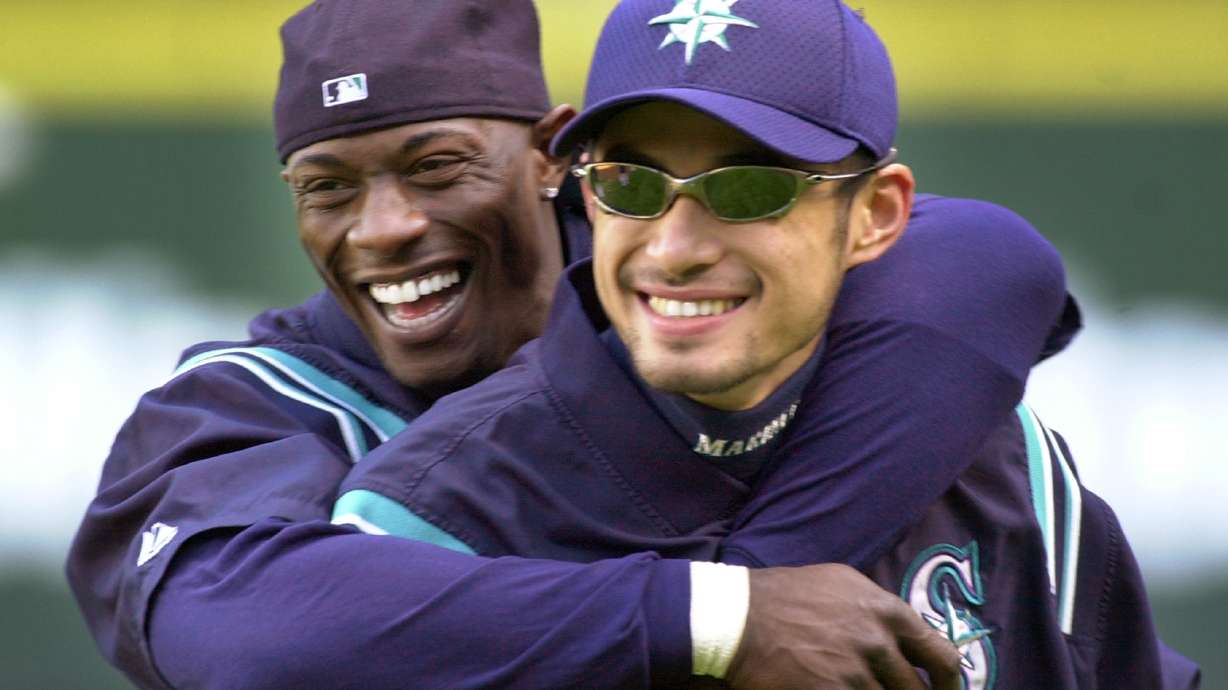 FILE - Seattle Mariners' Mike Cameron, left, embraces teammate Ichiro Suzuki during their workout Monday, Oct. 8, 2001, in Seattle. An entire generation has waited for the Seattle Mariners to bring playoff baseball back to the Pacific Northwest. After a 21-year absence, the postseason is back in Seattle for Game 3 of the ALDS against Houston.