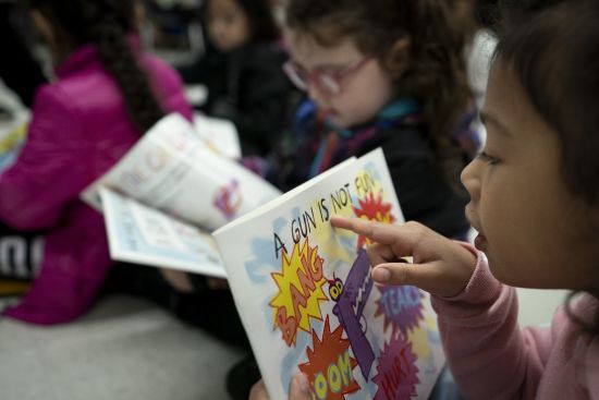 Children read as Ian Ellis James, an Emmy award-winning Sesame Street writer known by his stage name William Electric Black, leads a first grade class in a book reading on urban gun violence prevention at the Drexel Avenue School, Oct. 3 in Westbury, N.Y. Sales of books for young readers on violence, grief, and emotions have increased for nine straight years, according to NPD BookScan, which tracks U.S. retail sales of print books.