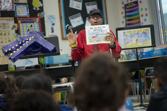Ian Ellis James, an Emmy award-winning Sesame Street writer known by his stage name William Electric Black, leads a first grade class in a book reading on urban gun violence prevention at the Drexel Avenue School, Oct. 3 in Westbury, New York. Black  is the author of the illustrated children’s book “A Gun Is Not Fun.” He said young children in areas afflicted by gun violence are more aware of it than parents may think.