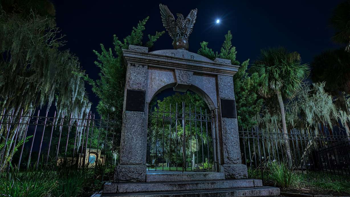 The gate to the Colonial Park Cemetery in Savanah, Georgia, at night, with the moon shining bright upon thousands of souls buried there.