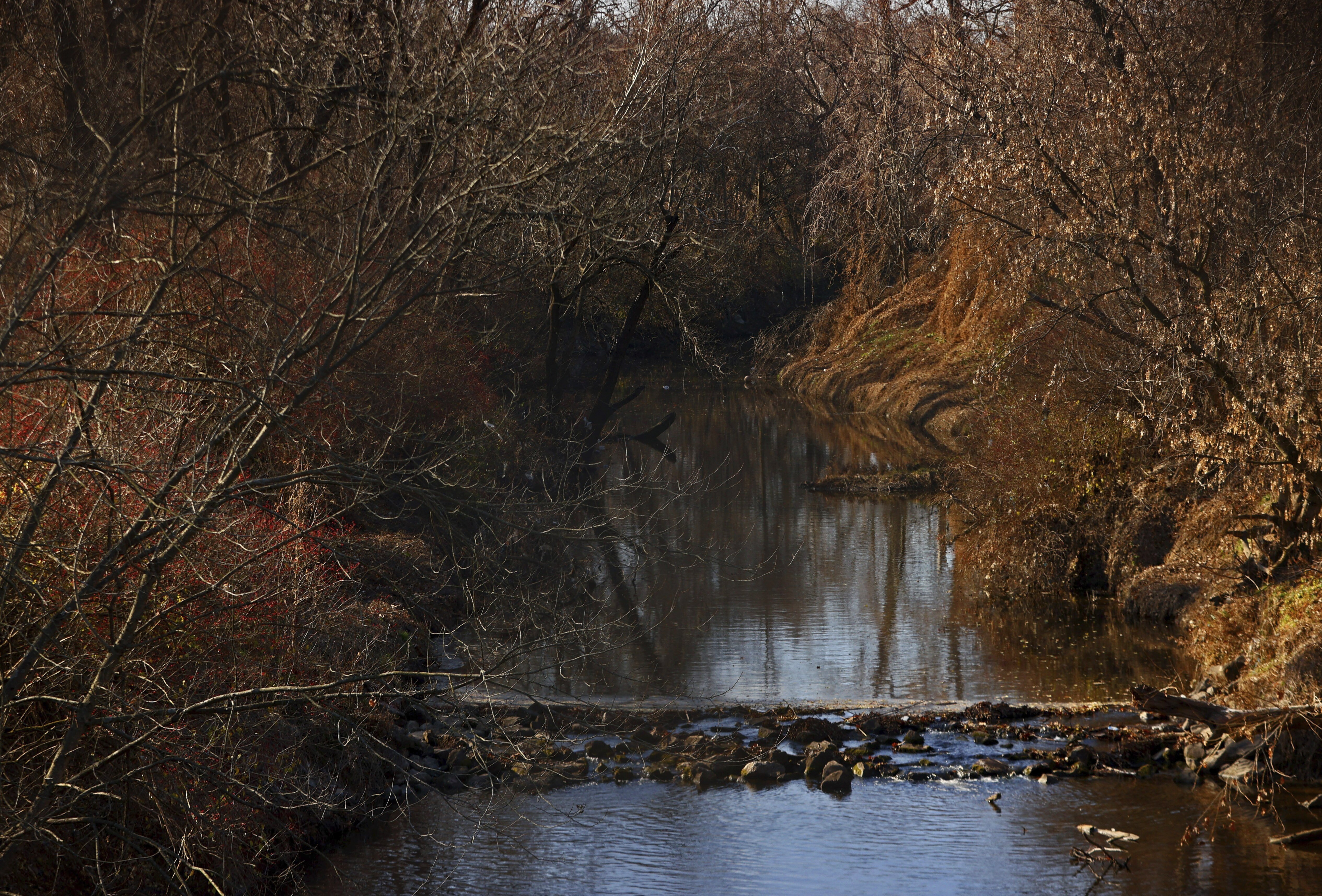 Water flows in Coldwater Creek on Thursday, Dec. 9, 2021, behind a row of homes at Belcroft Drive and Old Halls Ferry Road in Missouri's St. Louis County. Environmental investigation consultants have found significant radioactive contamination at an elementary school in suburban St. Louis where nuclear weapons were produced during World War II. 