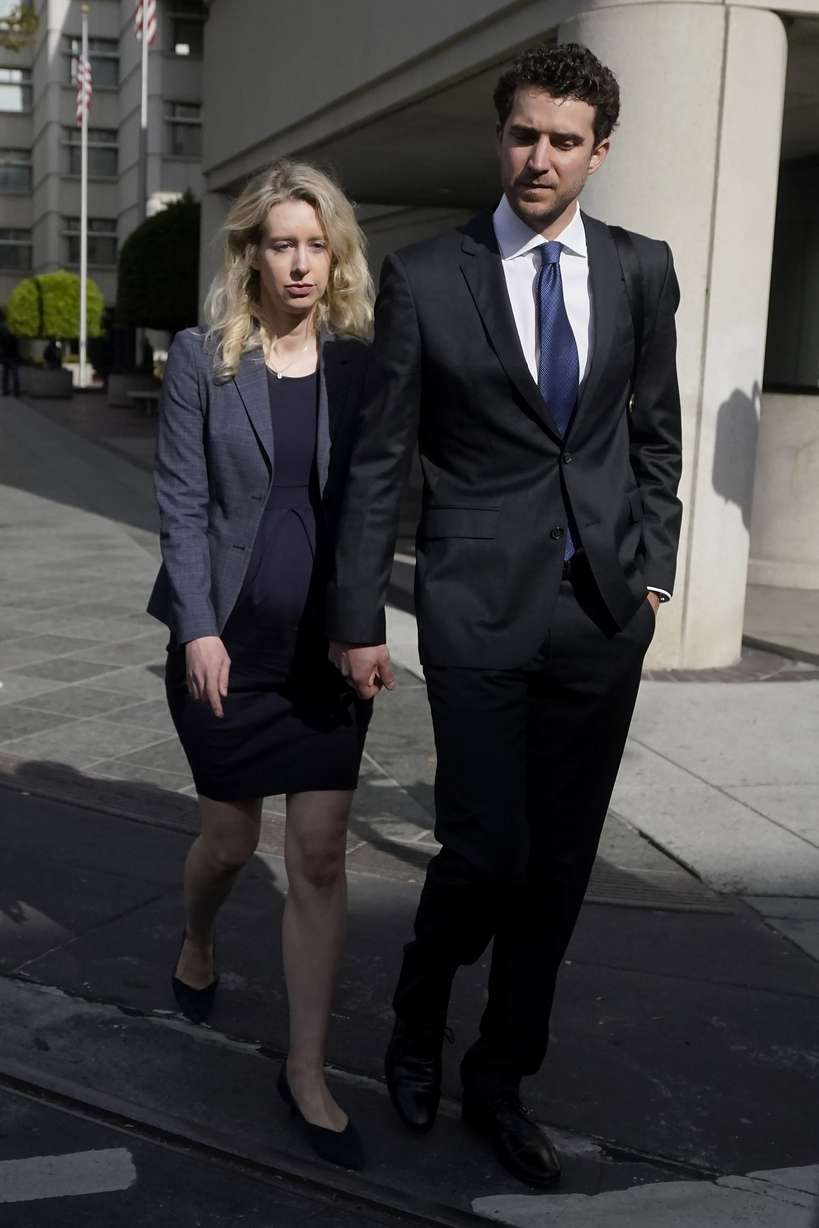 Former Theranos CEO Elizabeth Holmes, left, walks with her partner, Billy Evans, after leaving federal court in San Jose, Calif., Oct. 17.