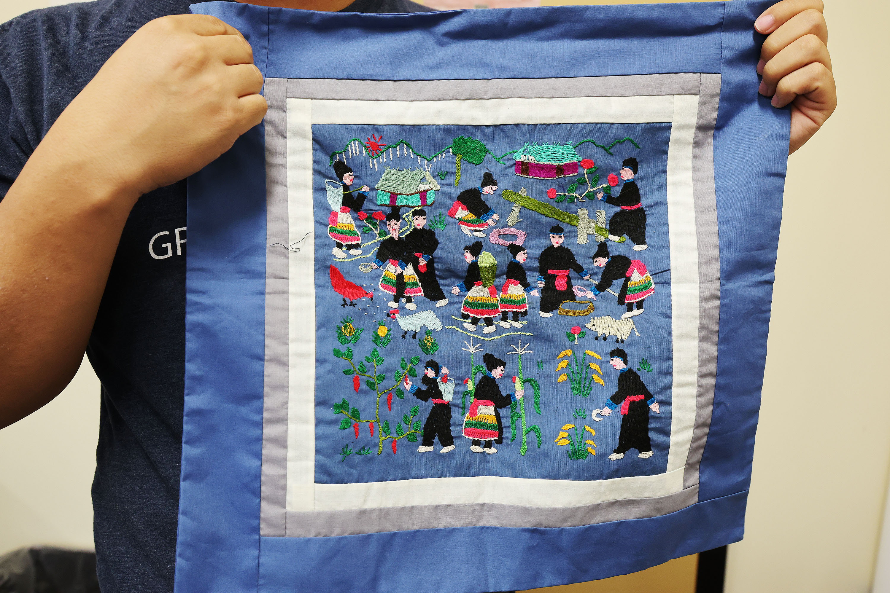 Yang Vang, a Brigham Young University master's degree candidate in anthropology and world-renowned Hmong shaman, holds an embroidered family history in Provo on Oct. 13.