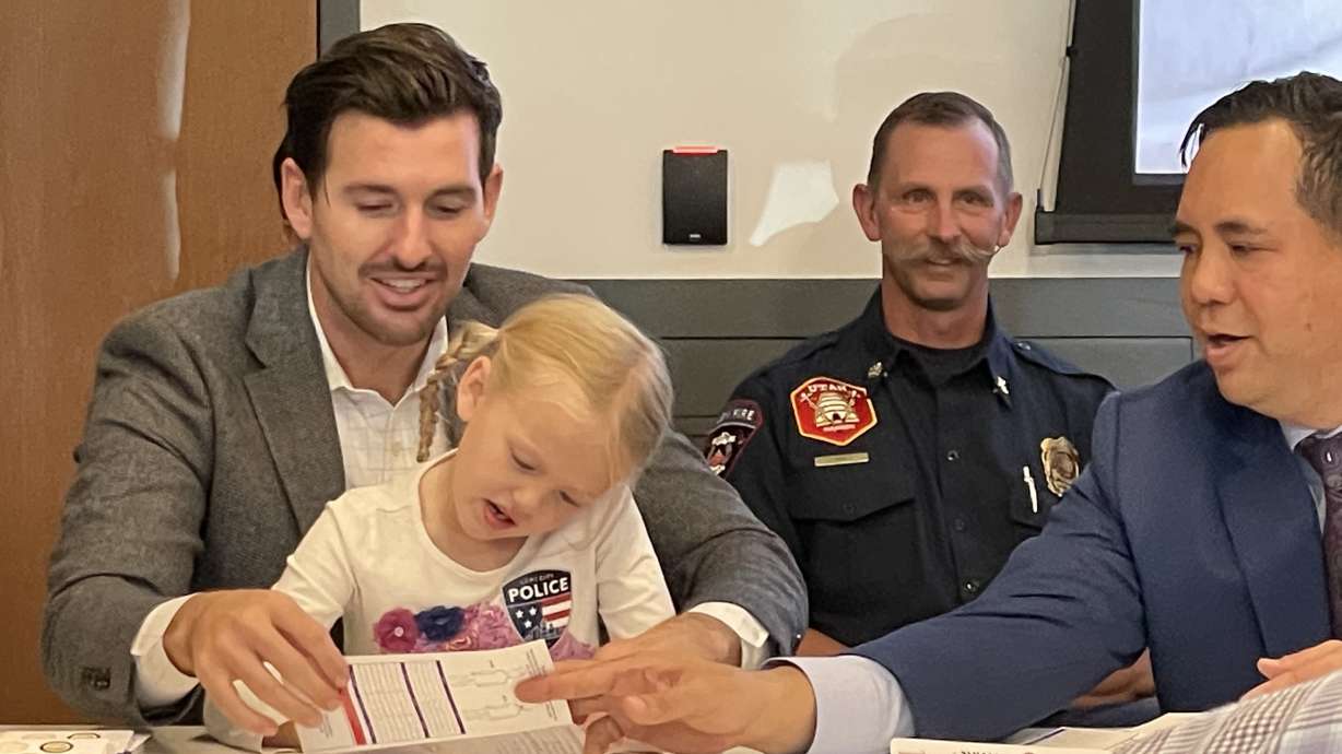 Marlon Bateman and his daughter, 6, demonstrate how to complete a child ID kit along with Utah Attorney General Sean Reyes in Lehi on Tuesday.