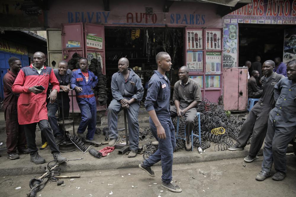 Workers gather as they wait for customers outside a secondhand car parts shop in the industrial area of the capital Nairobi, Kenya, Oct 7. In a gritty neighborhood of Nairobi known for fixing cars and selling auto parts, businesses are struggling and customers are unhappy.