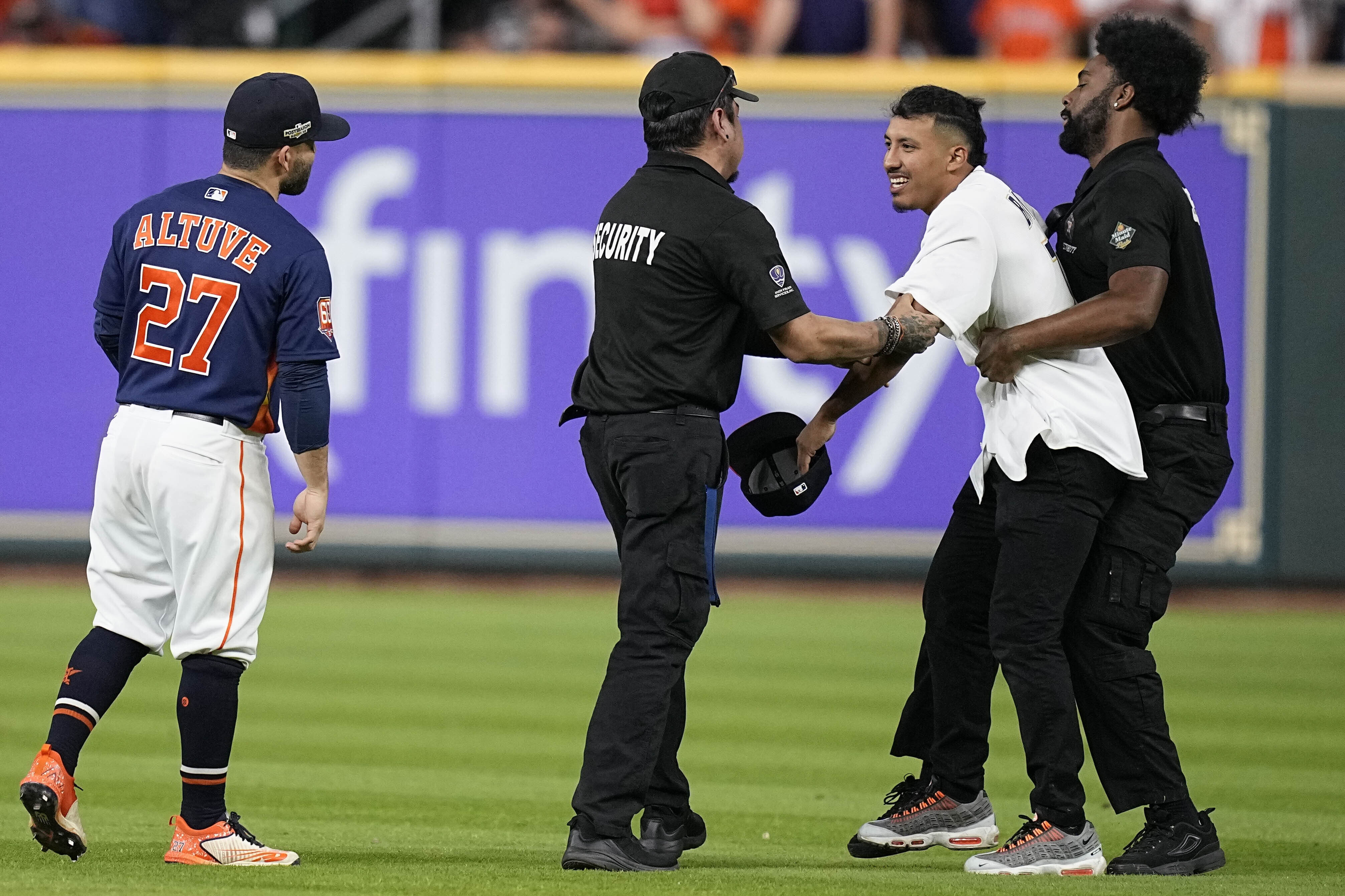 Security remove a fan on the field in between the eighth and ninth innings in Game 2 of baseball's American League Championship Series between the Houston Astros and the New York Yankees, Thursday, Oct. 20, 2022, in Houston. 