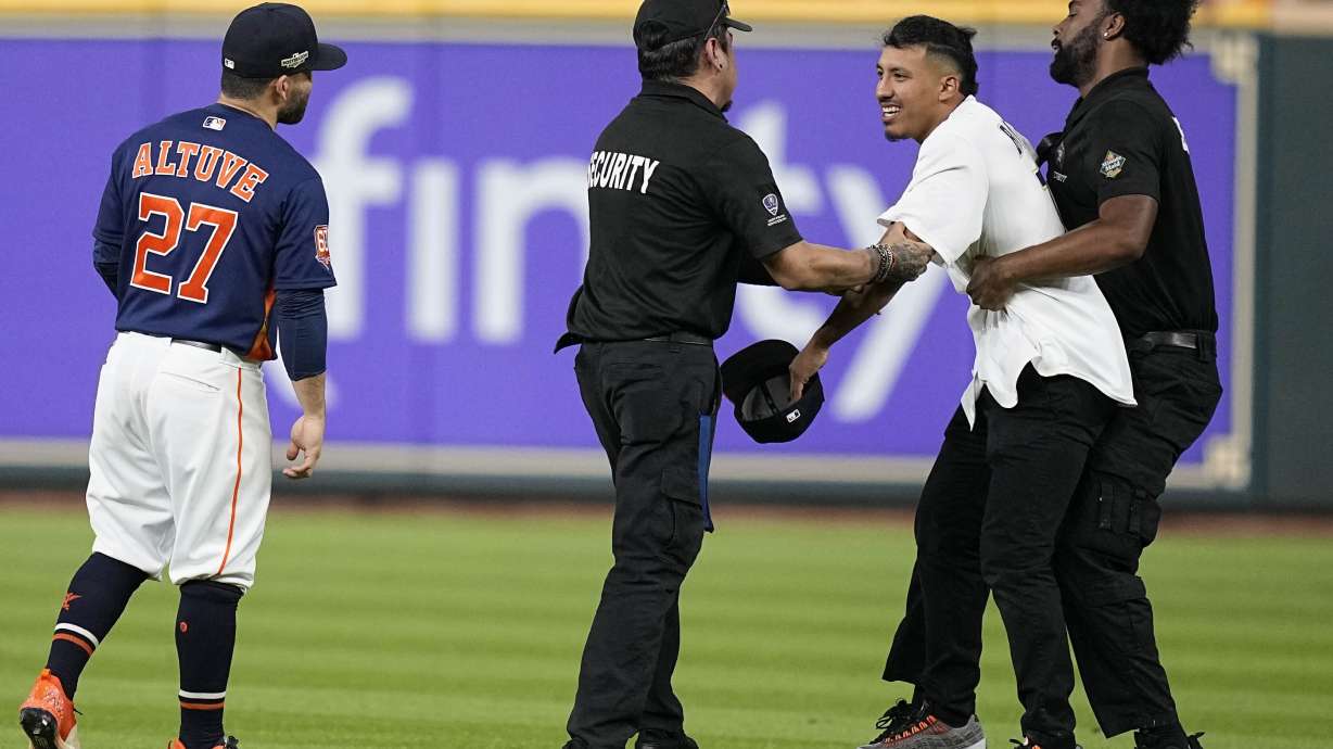 Security remove a fan on the field in between the eighth and ninth innings in Game 2 of baseball's American League Championship Series between the Houston Astros and the New York Yankees, Thursday, Oct. 20, 2022, in Houston.