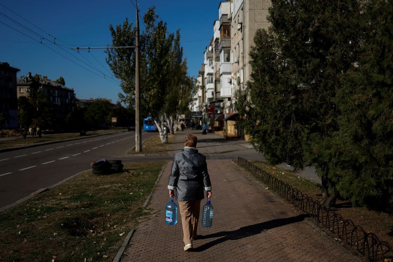 A local woman carries filled bottles of fresh drinking water, as the main supply pipeline for drinking water for the city was damaged in Kherson region at the beginning of Russia's attack on Ukraine, in Mykolaiv, Ukraine, Oct. 16.