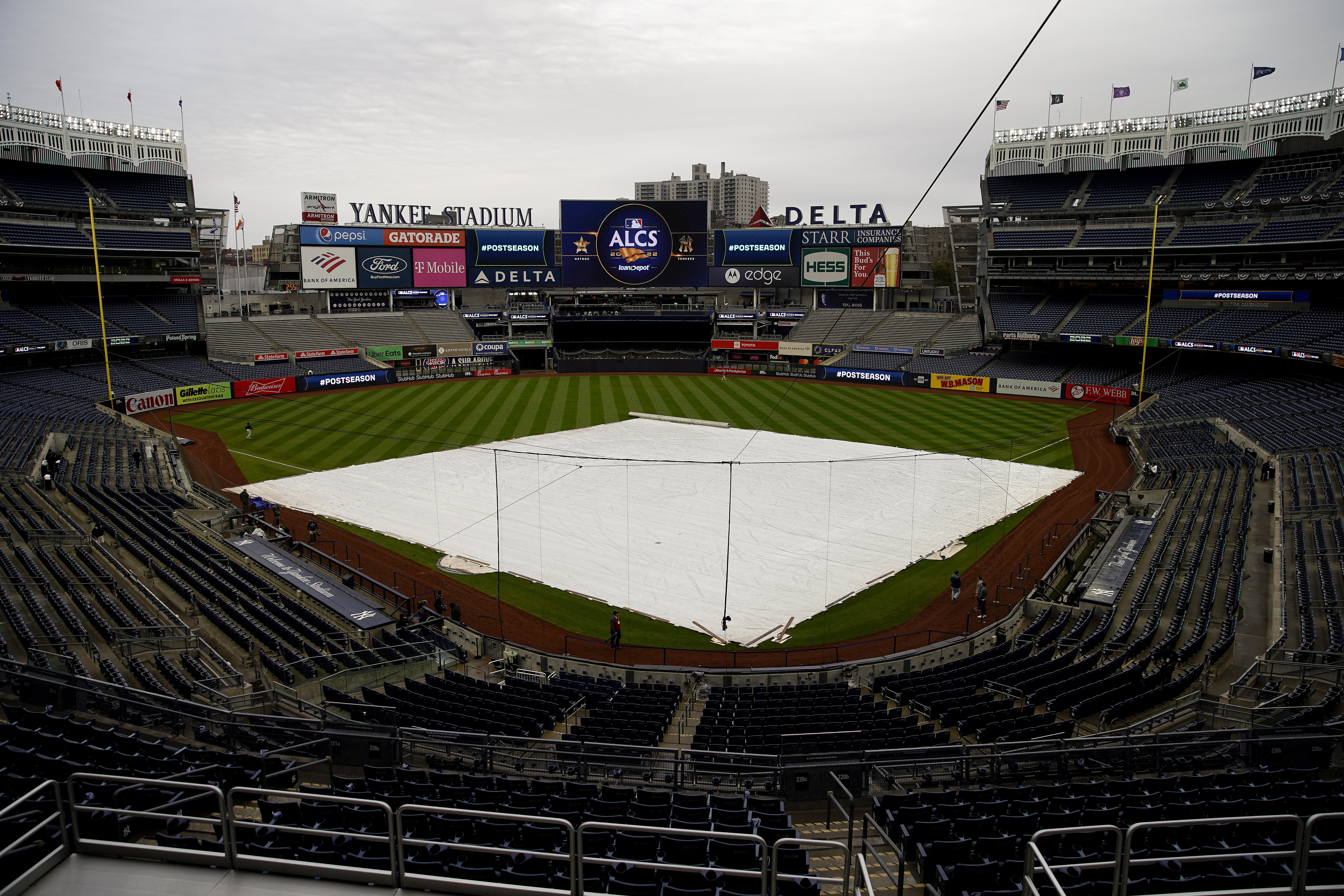 The rain tarp covers the field as a light rain falls on Yankee Stadium before Game 4 of an American League Championship baseball series between the New York Yankees and the Houston Astros, Sunday, Oct. 23, 2022, in New York. 