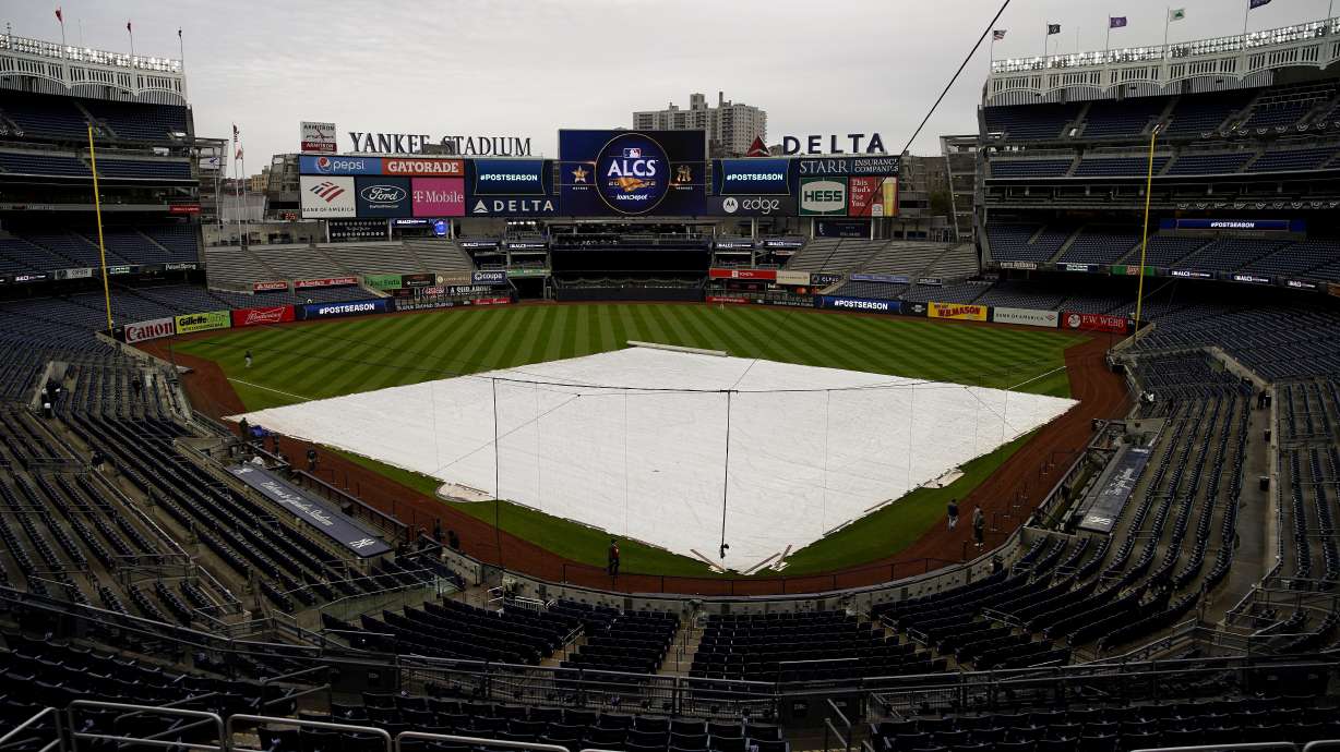 The rain tarp covers the field as a light rain falls on Yankee Stadium before Game 4 of an American League Championship baseball series between the New York Yankees and the Houston Astros, Sunday, Oct. 23, 2022, in New York.