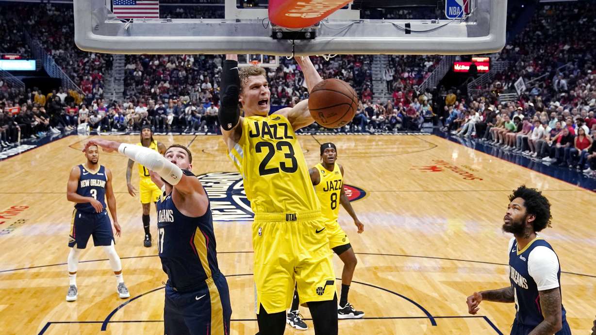 Utah Jazz forward Lauri Markkanen (23) slam dunks over New Orleans Pelicans center Jonas Valanciunas, left, and forward Brandon Ingram, right, in the first half of an NBA basketball game in New Orleans, Sunday, Oct. 23, 2022.