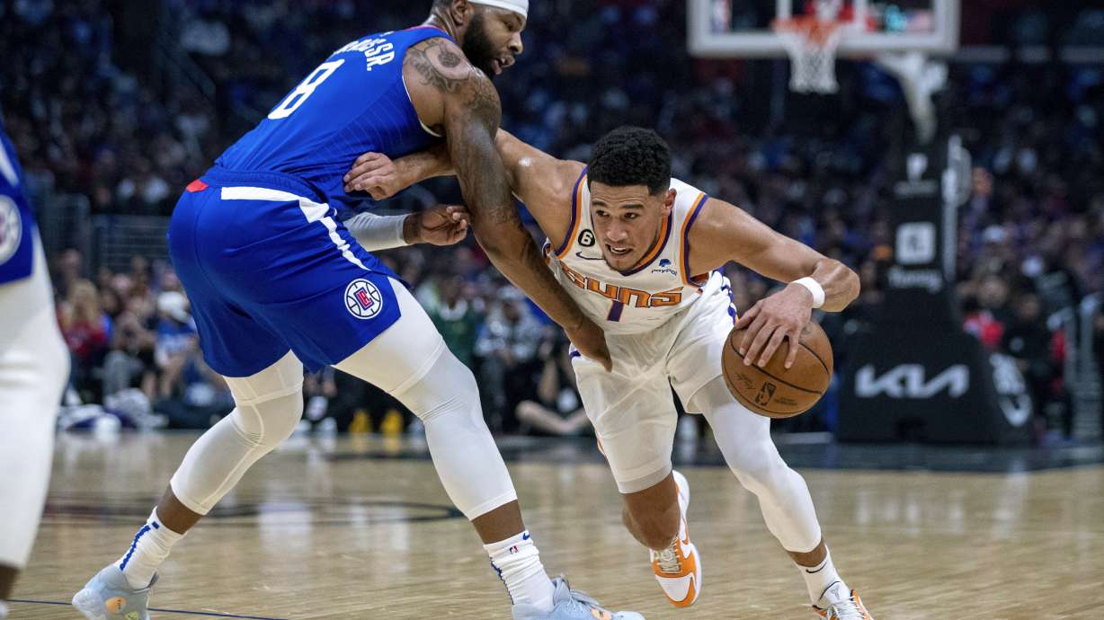 Phoenix Suns guard Devin Booker, right, drives past Los Angeles Clippers forward Marcus Morris Sr., during the first half of an NBA basketball game, Sunday, Oct. 23, 2022 in Los Angeles.