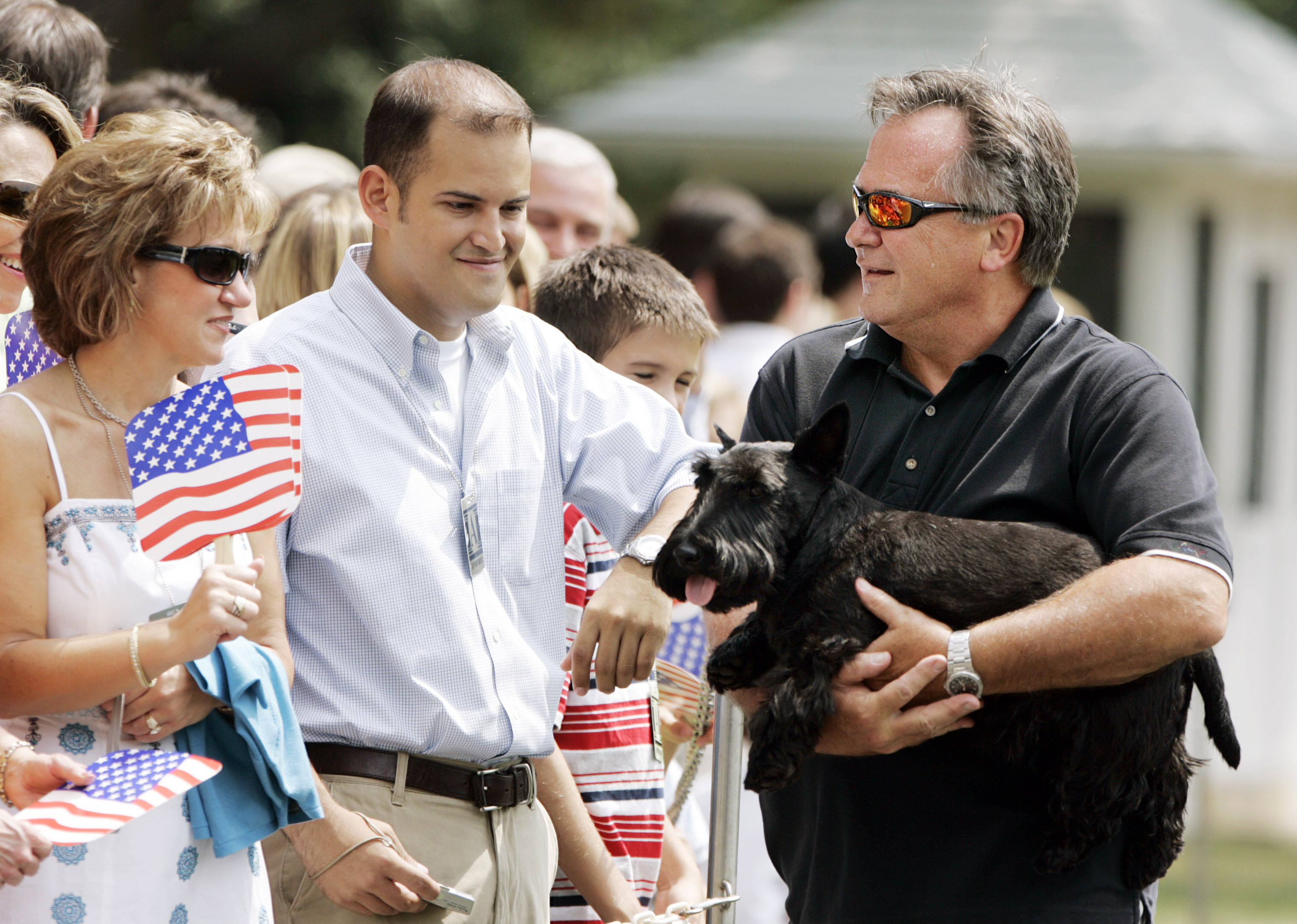 White House horticulturist Dale Haney, right, holds presidential pet Barney, as visitors wait for then-President George W. Bush and then-first lady Laura Bush's arrival on the South Lawn at the White House, Aug. 20, 2006, in Washington. 