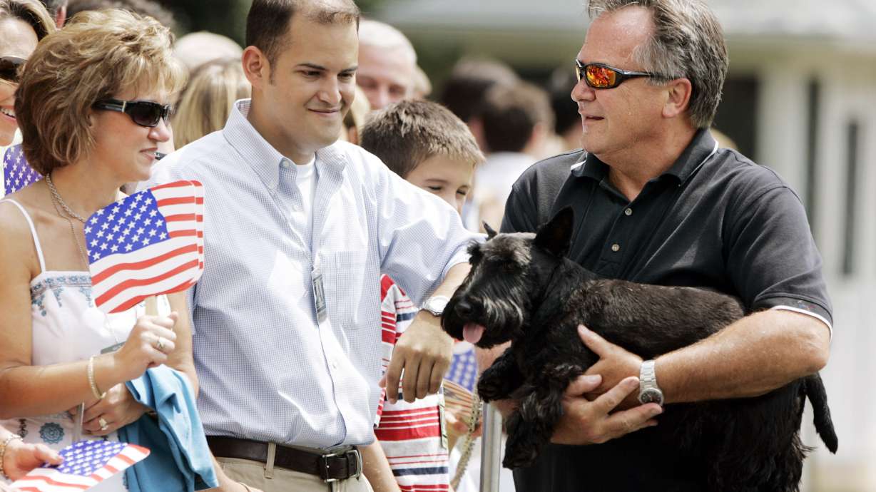 White House horticulturist Dale Haney, right, holds presidential pet Barney, as visitors wait for then-President George W. Bush and then-first lady Laura Bush's arrival on the South Lawn at the White House, Aug. 20, 2006, in Washington.