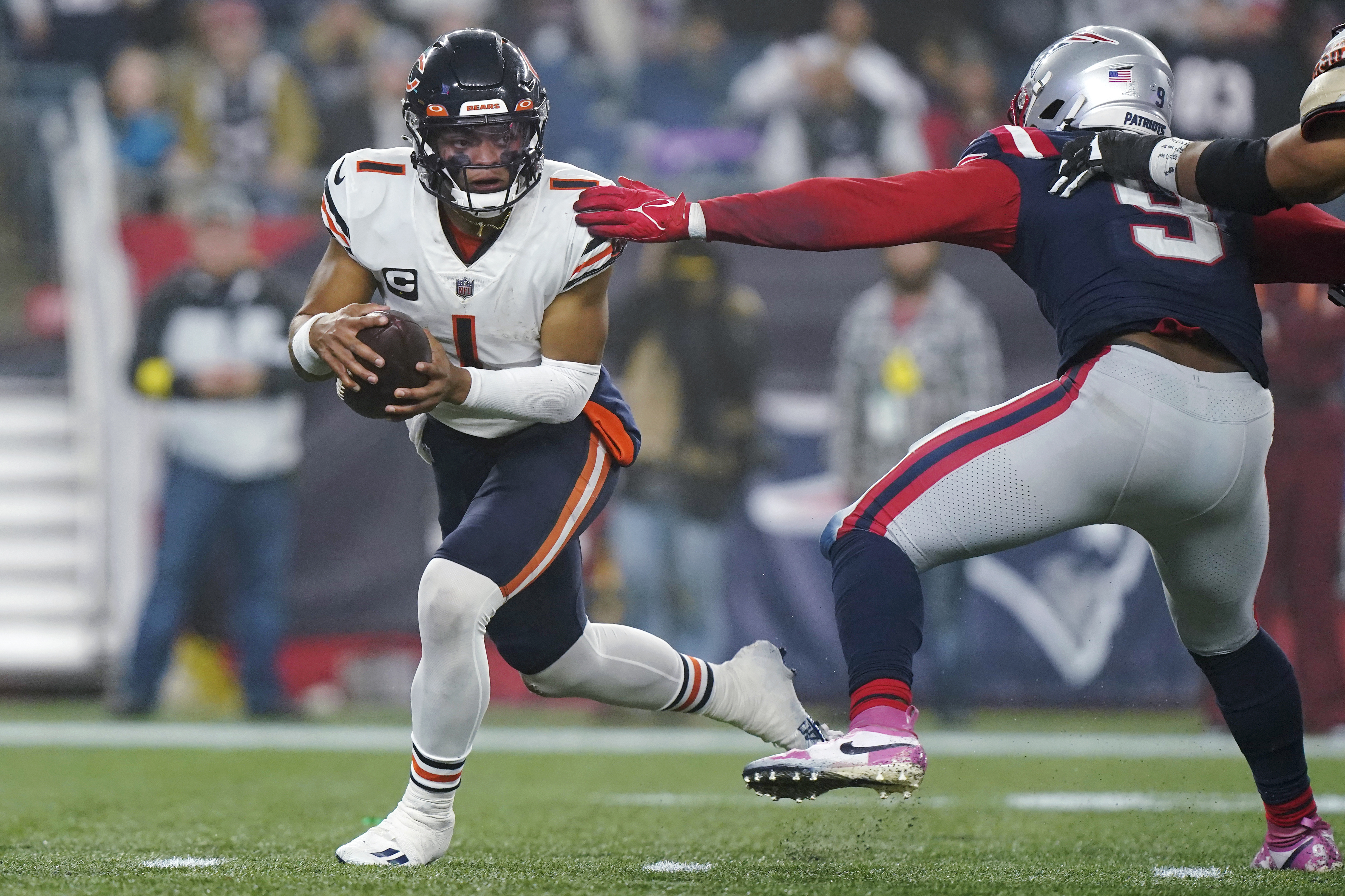 Chicago Bears quarterback Justin Fields (1) eludes New England Patriots linebacker Matthew Judon (9) during the second half of an NFL football game, Monday, Oct. 24, 2022, in Foxborough, Mass. 