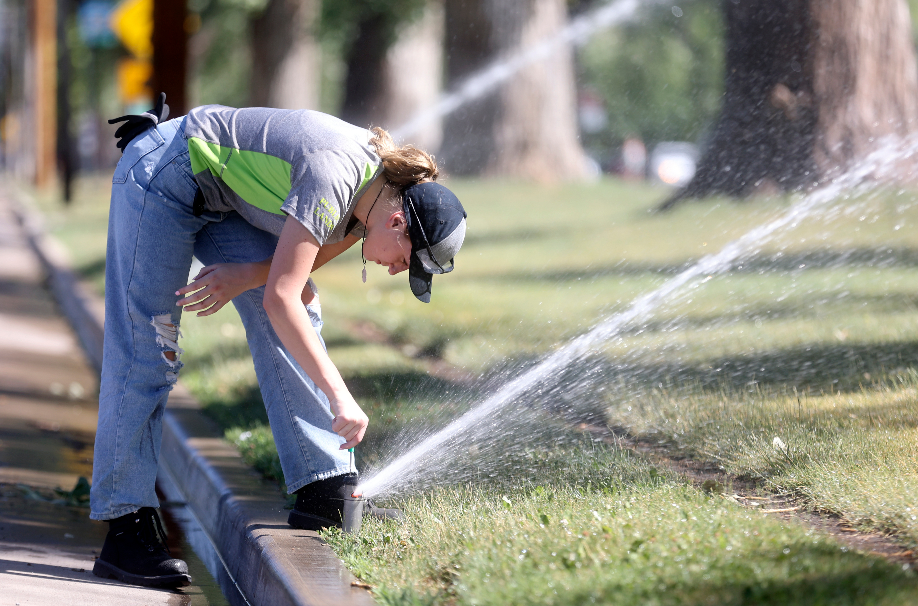 Riley Niederhauser, a Salt Lake City Public Lands Department crew member, repairs sprinklers in Liberty Park in Salt Lake City on July 7. A new analysis published by the Utah Rivers Council Wednesday critiques the state's water district property tax, but water suppliers say it's crucial for funding water projects. 