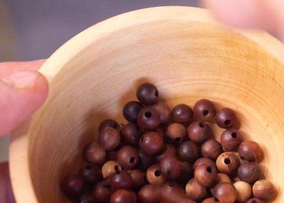 Justin Davies shows a bowl of mahogany beads made from the first piece of wood — mountain mahogany — he collected from a trail in the summer of 2021.
