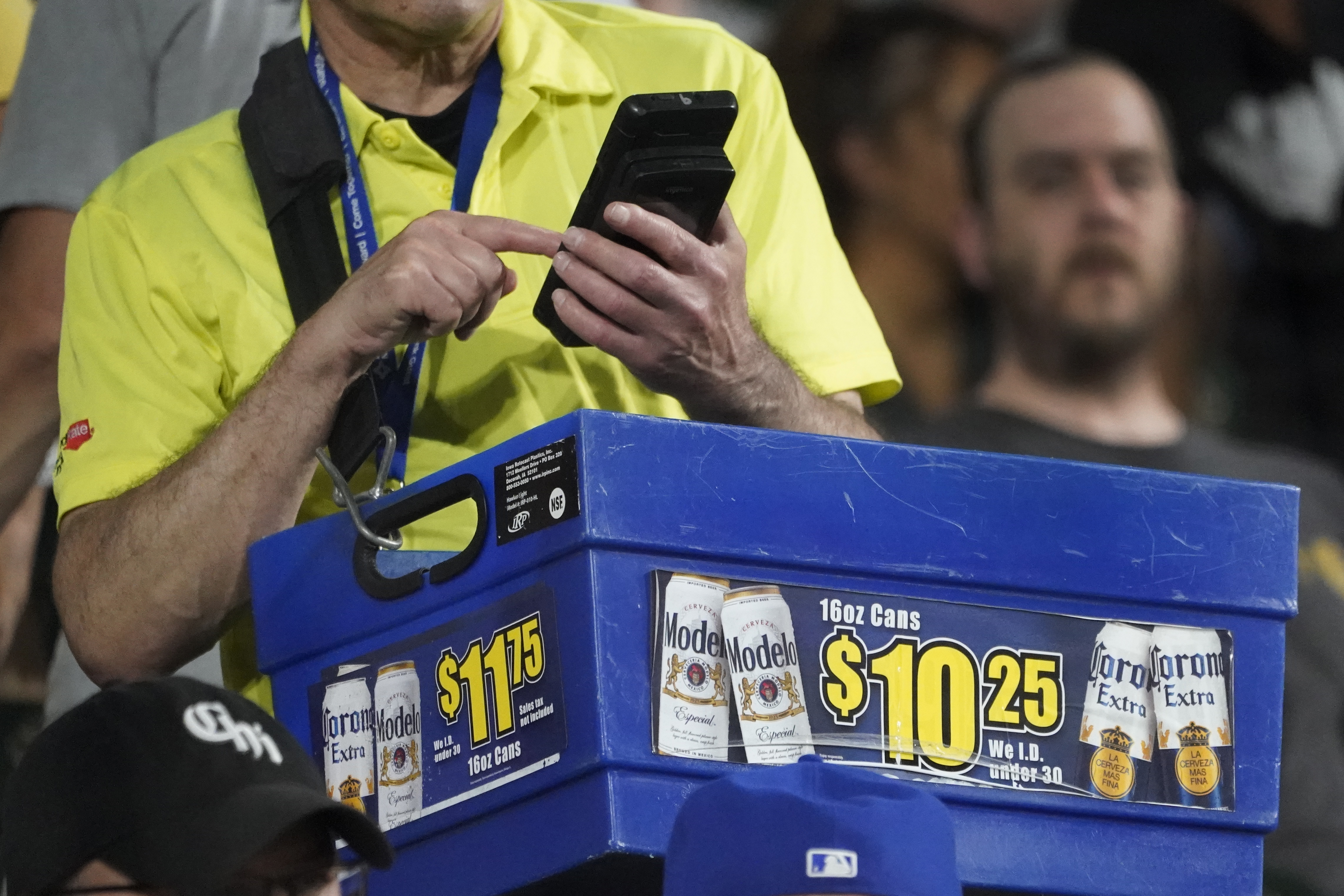 A beer vendor figures out the price for a baseball fan during a baseball game between the Cleveland Guardians and Chicago White Sox Tuesday, Sept. 20, 2022, in Chicago. Persistently high inflation and gas prices are looming over sports and the monetary pipeline that resumed when fans returned to games amid the pandemic.