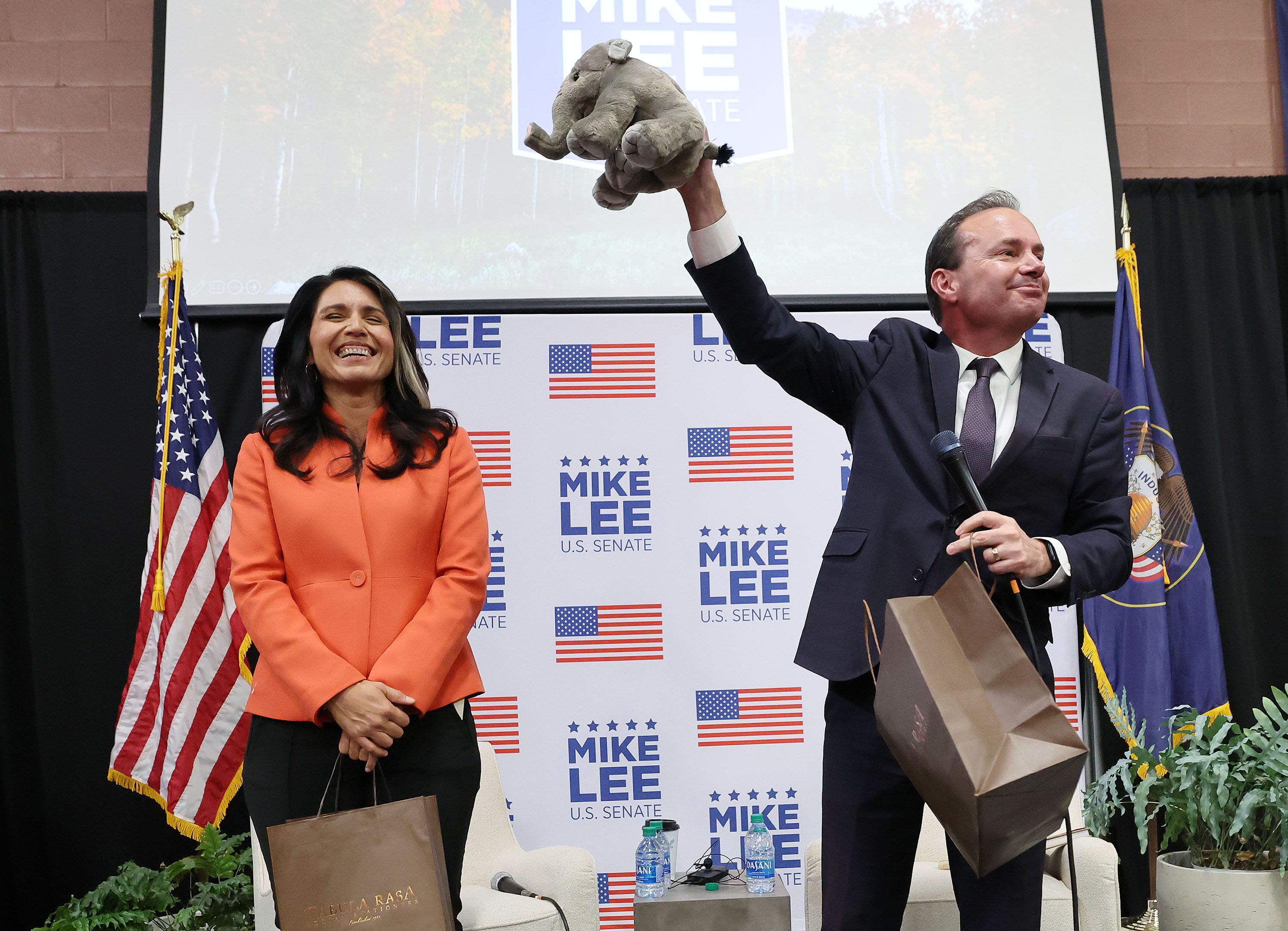 Sen. Mike Lee, R-Utah, gives former Democratic Rep. Tulsi Gabbard, D-Hawaii, a stuffed elephant as she campaigns for him during a rally at the American Preparatory Academy in Draper on Thursday.