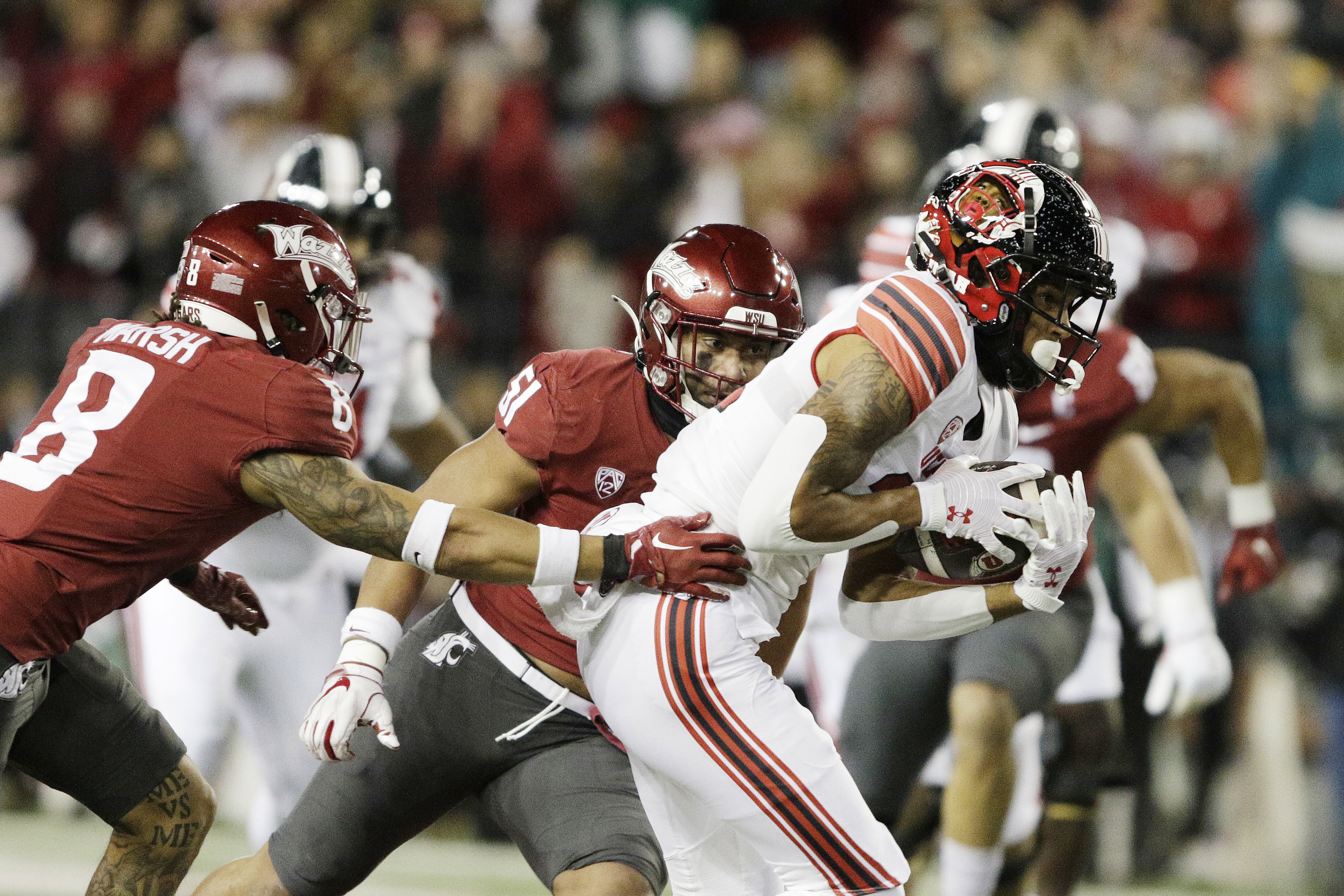Utah wide receiver Solomon Enis, right, carries the ball while pressured by Washington State defensive back Armani Marsh, left, and linebacker Francisco Mauigoa during the first half of an NCAA college football game, Thursday, Oct. 27, 2022, in Pullman, Wash. 