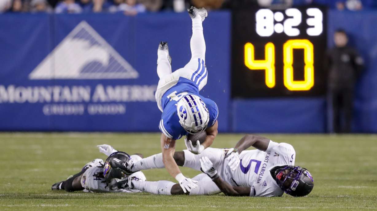 BYU running back Lopini Katoa (4) flies through the air after being hit by East Carolina's Jireh Wilson (5) in an NCAA college football game Friday, Oct. 28, 2022, in Provo. The Pirates won 27-24.