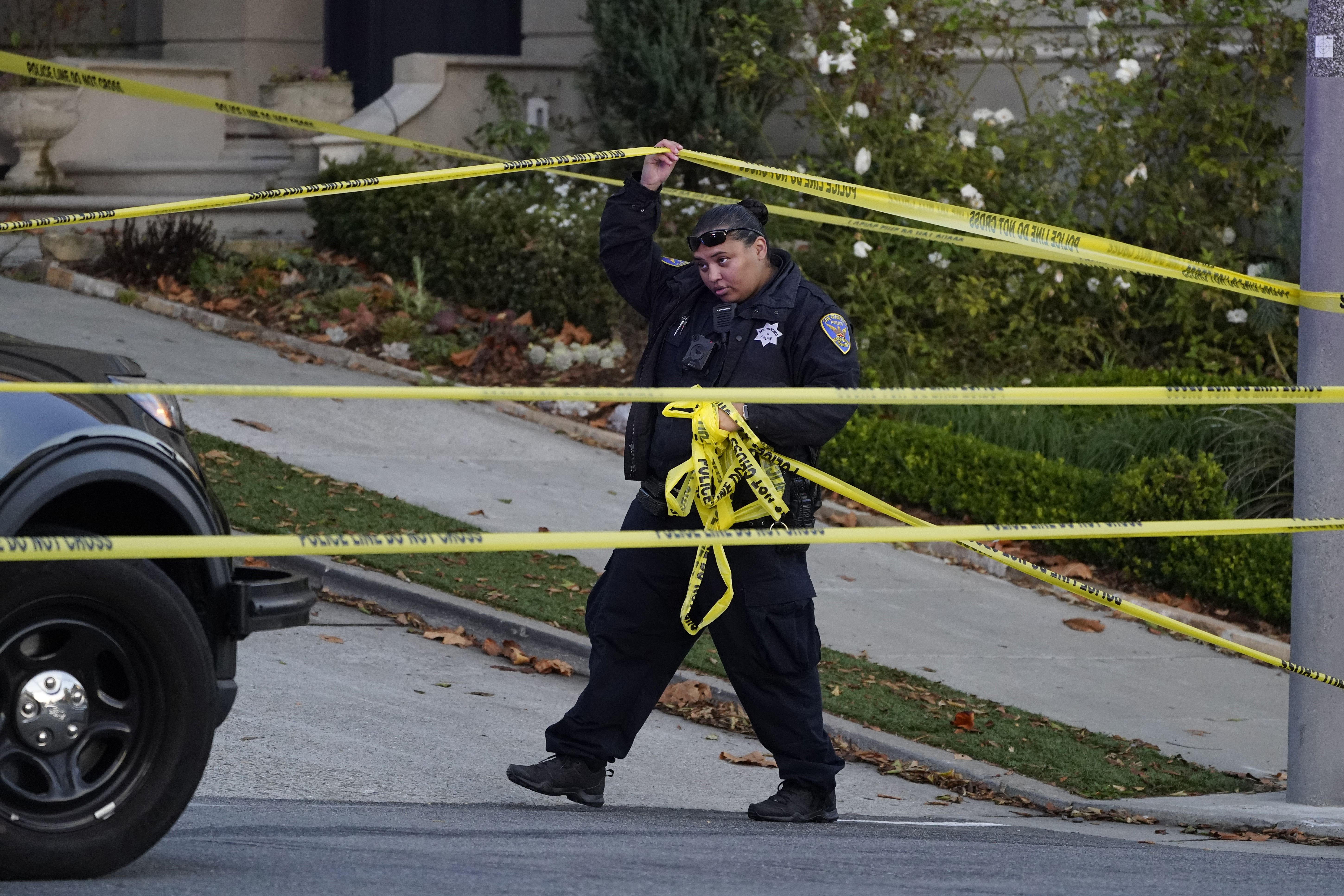 A police officer rolls out more yellow tape on the closed street below the home of Paul Pelosi, the husband of House Speaker Nancy Pelosi, in San Francisco, Friday. Paul Pelosi, was attacked and severely beaten by an assailant with a hammer who broke into their San Francisco home early Friday, according to people familiar with the investigation.