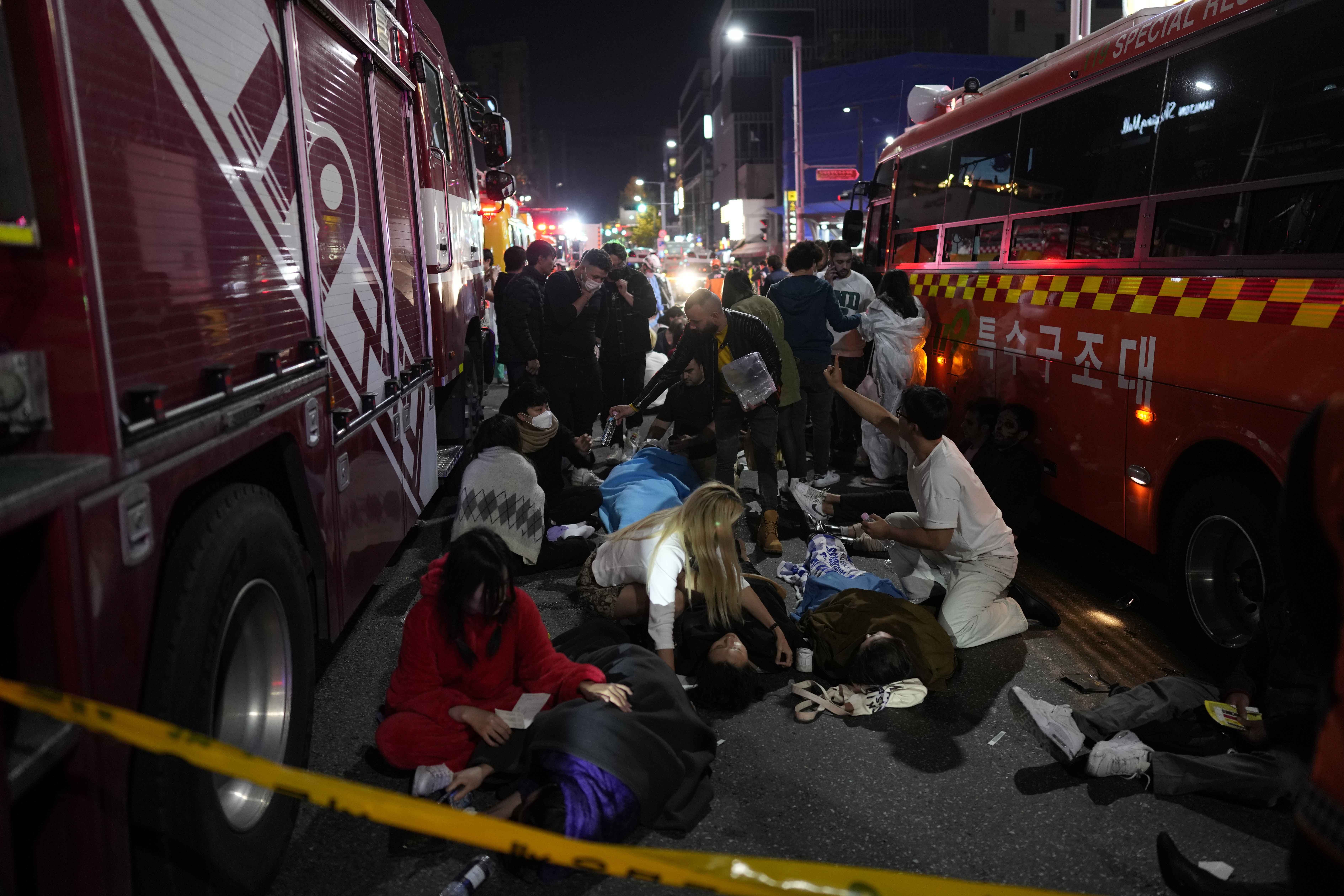Injured people are helped on the street near the scene in Seoul, South Korea, early Sunday, Oct. 30. South Korean officials said around 50 people were in cardiac arrest and a number feared dead after being crushed by a large crowd pushing forward on a narrow street during Halloween festivities in the capital Seoul.