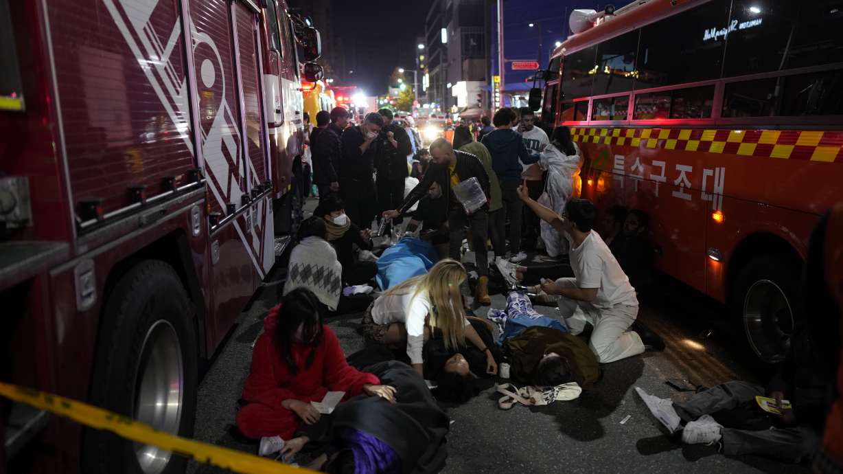 Injured people are helped at the street near the scene in Seoul, South Korea, early Sunday. South Korean officials said around 50 people were in cardiac arrest and a number feared dead after being crushed by a large crowd pushing forward on a narrow street during Halloween festivities in the capital Seoul.