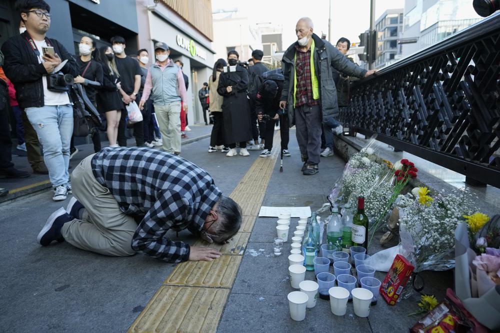 A man bows to pay tribute to victims near the scene of a deadly accident in Seoul, South Korea, Sunday, following Saturday night's Halloween festivities. A mass of mostly young people among tens of thousands who gathered to celebrate Halloween in Seoul became trapped and crushed as the crowd surged into a narrow alley, killing dozens of people and injuring dozens of others in South Korea’s worst disaster in years.