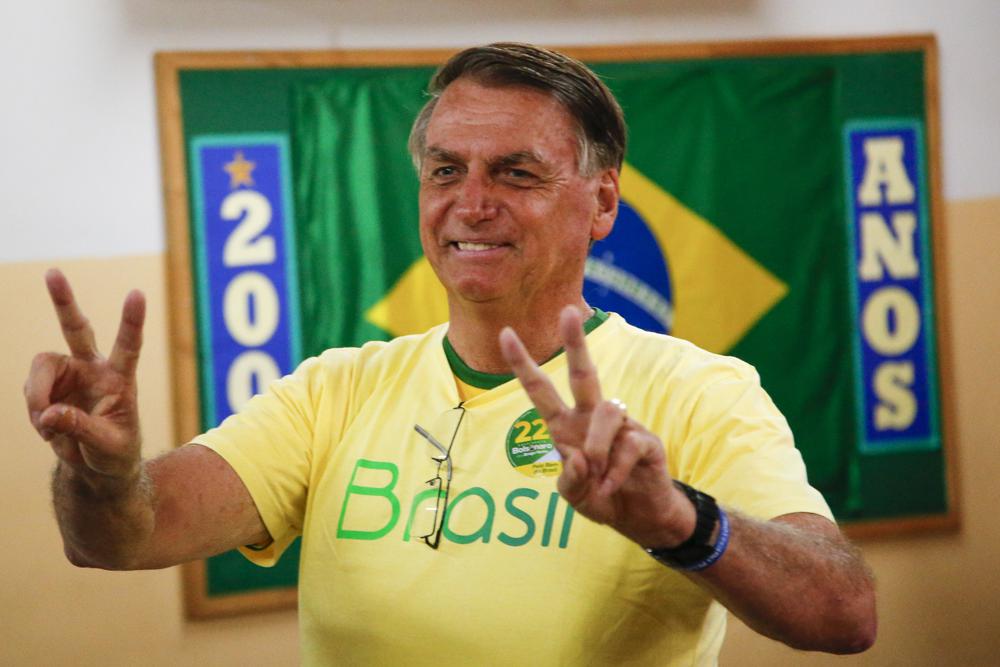 Brazilian President Jair Bolsonaro, who has not concede the tight runoff election results, makes the victory sign after voting in a second round presidential election in Rio de Janeiro, Brazil, Sunday.