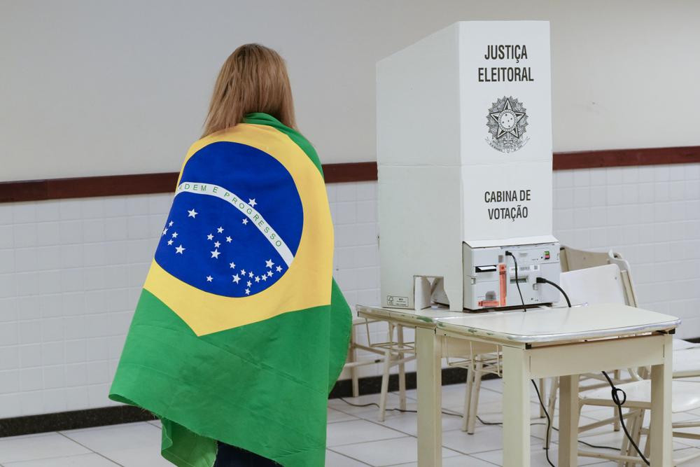 A voter wrapped in a Brazilian flag arrives to vote in a presidential a run-off pitting President Jair Bolsonaro against former President Luiz Inácio Lula da Silva, in Brasilia, Brazil, Sunday.