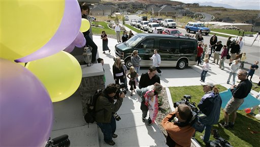 Jake Herrin carries his daughter, one of the formerly conjoined twins, Maliyah, into their home while being surrounded by media, neighbors, family and balloons Sunday, Sept. 17, 2006, in North Salt Lake, Utah. The two girls, Kendra and Maliyah, were separated last month. (AP Photo/Douglas C. Pizac)