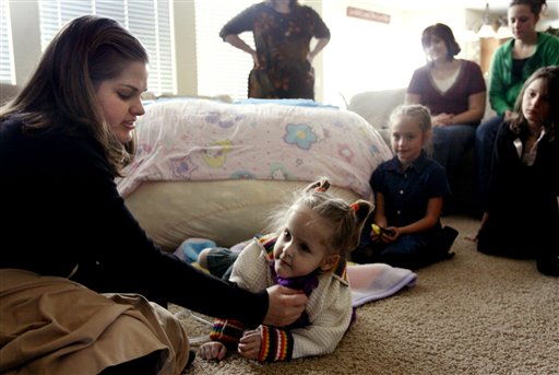 Formerly conjoined twin, Kendra Herrin, crawls for the first time after being separated from her sister next to her mother, Erin, at home Sunday, Sept. 17, 2006, in North Salt Lake, Utah. (AP Photo/Laura Seitz, Pool)