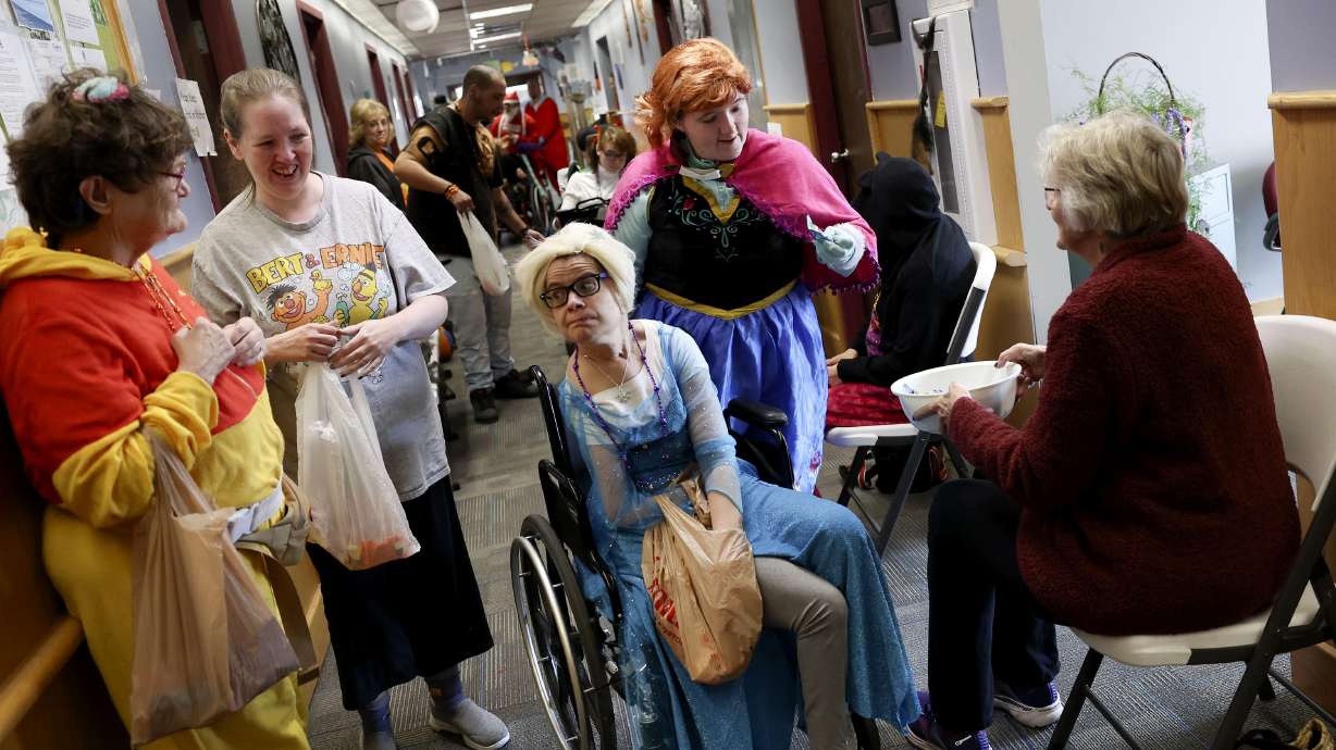 Tanna, center, dressed as Elsa from “Frozen,” and other clients of Together We Shine trick-or-treat at the center in Ogden on Monday. The services and support organization for adults with disabilities put on a Halloween trick-or-treat celebration for staff, clients and community members.