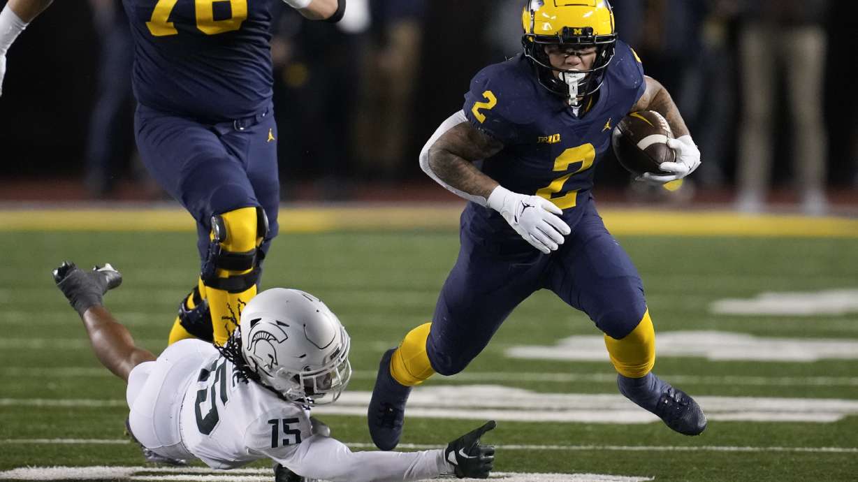 Michigan running back Blake Corum (2) escapes Michigan State safety Angelo Grose (15) in the first half of an NCAA college football game in Ann Arbor, Mich., Saturday, Oct. 29, 2022.