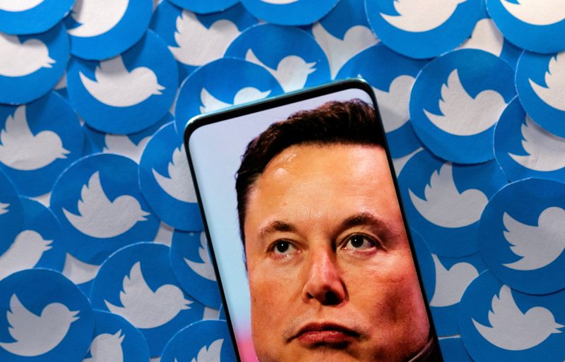 An image of Elon Musk is seen on a smartphone placed on printed Twitter logos in this picture illustration made April 28.