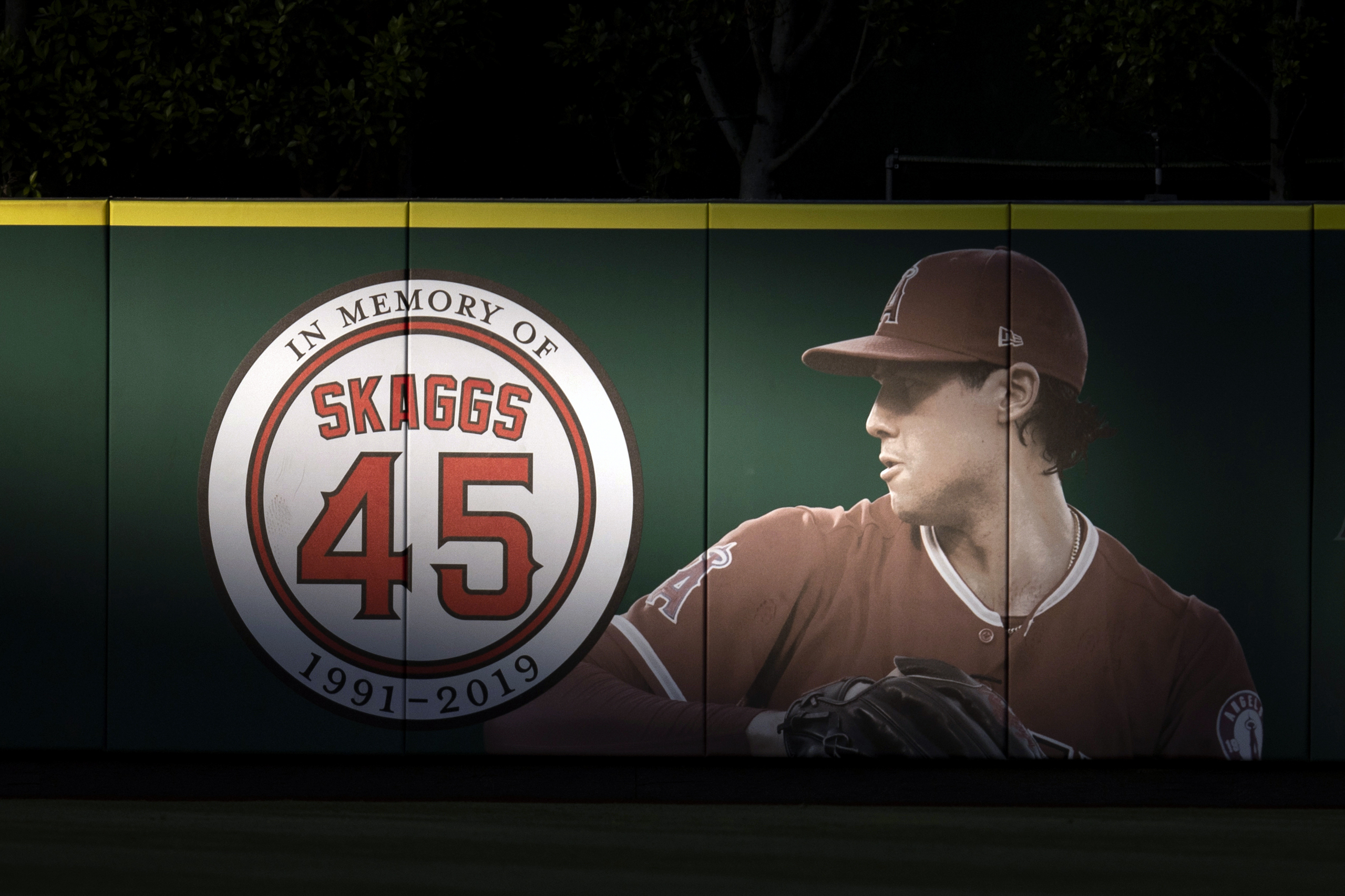 FILE - In this July 17, 2019, file photo, an image and logo memorializing former Los Angeles Angels pitcher Tyler Skaggs are displayed on the outfield wall in Anaheim, Calif. A California judge is allowing a lawsuit to proceed against the Angels over the drug-related death of Skaggs. 