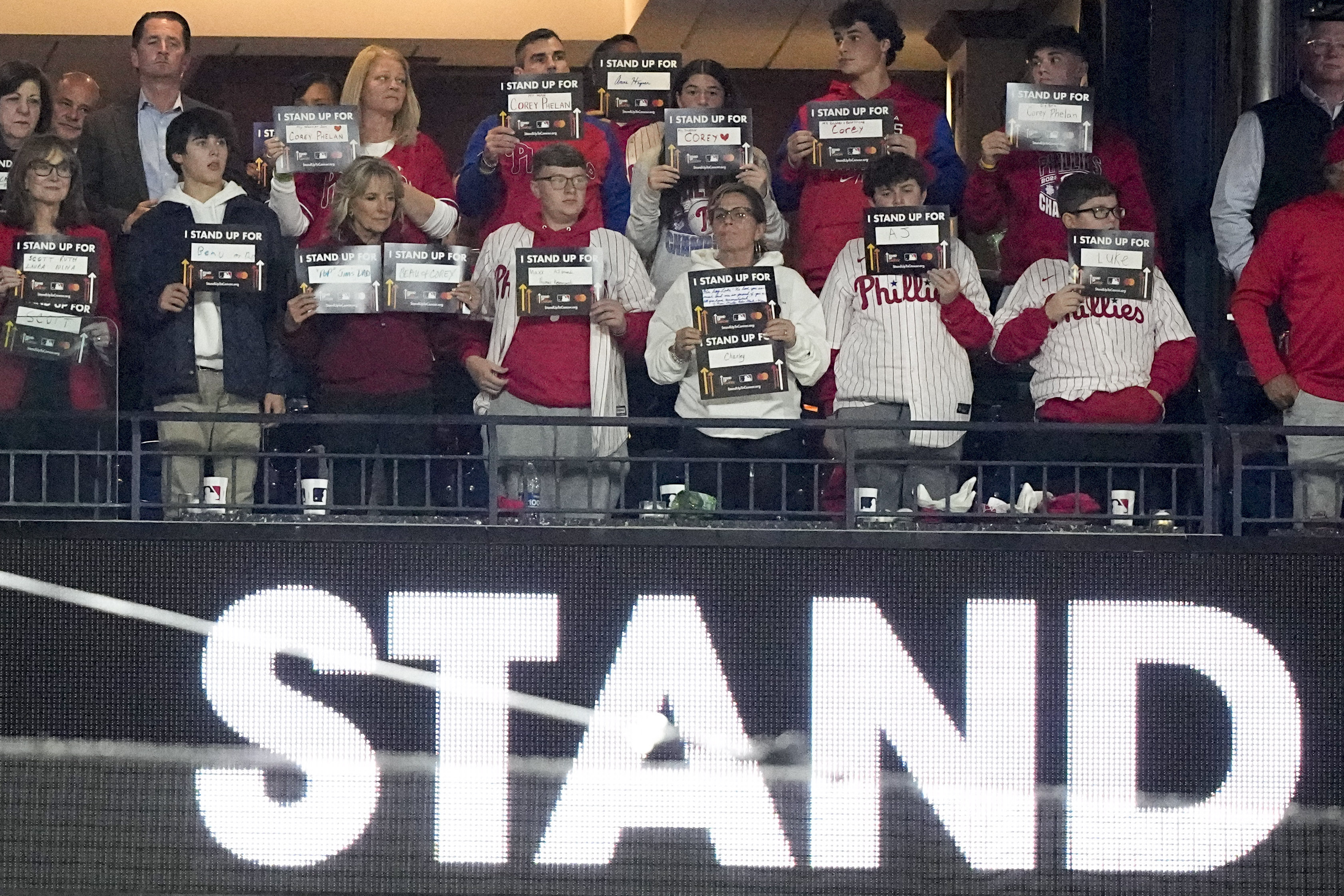 First Lady Jill Biden, third from left in front, hold signs for Stand Up To Cancer between the fifth and sixth innings in Game 4 of baseball's World Series between the Houston Astros and the Philadelphia Phillies on Wednesday, Nov. 2, 2022, in Philadelphia. 