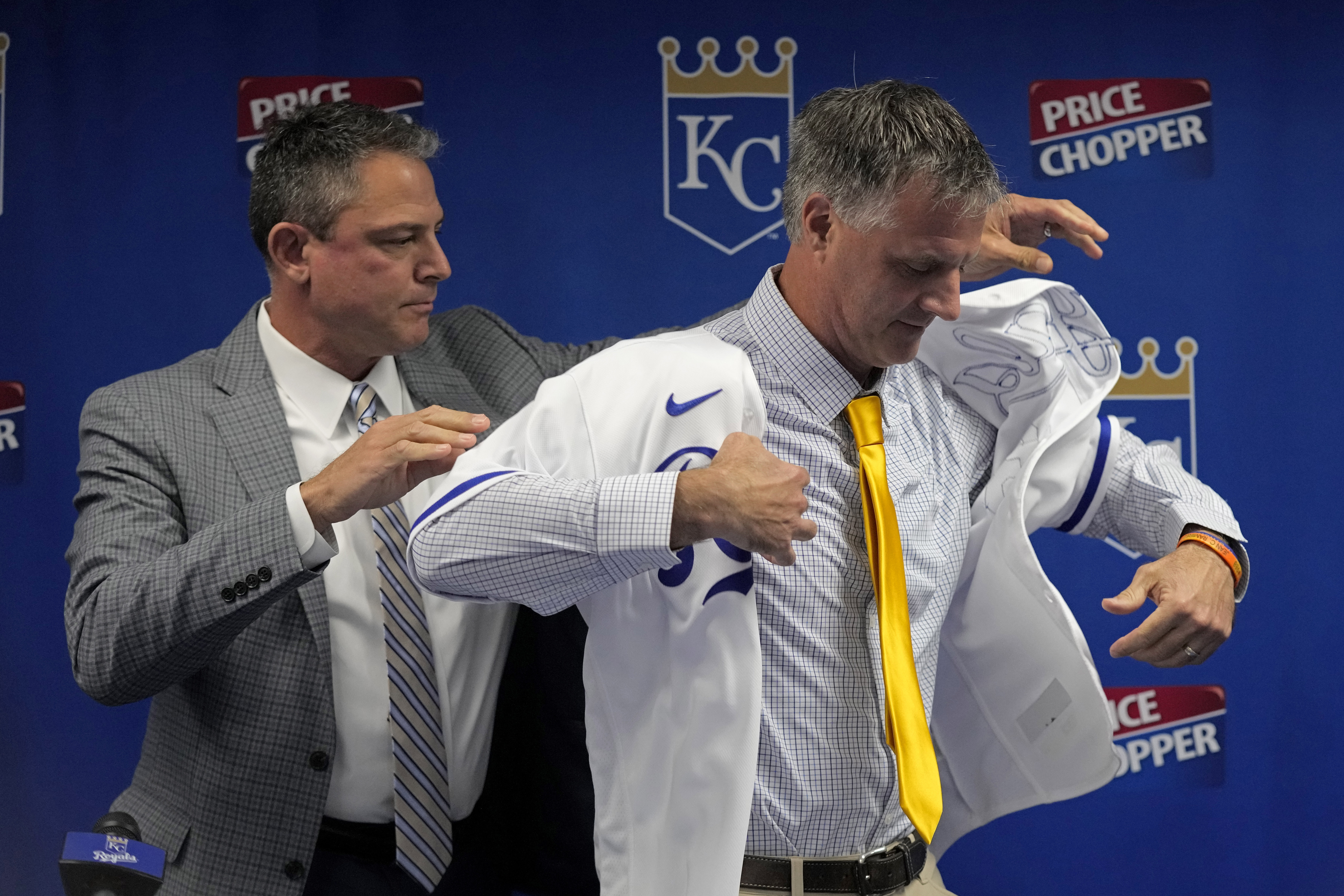 Matt Quatraro is helped by general manager J.J. Piccolo as he tries on a jersey during a news conference announcing him as the new manager of the Kansas City Royals Thursday, Nov. 3, 2022, in Kansas City, Mo. 