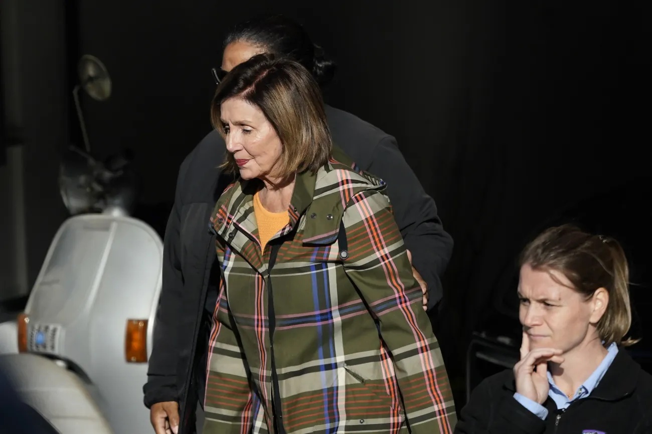 House Speaker Nancy Pelosi is escorted to a vehicle outside of her and husband Paul Pelosi’s home in San Francisco on Wednesday.