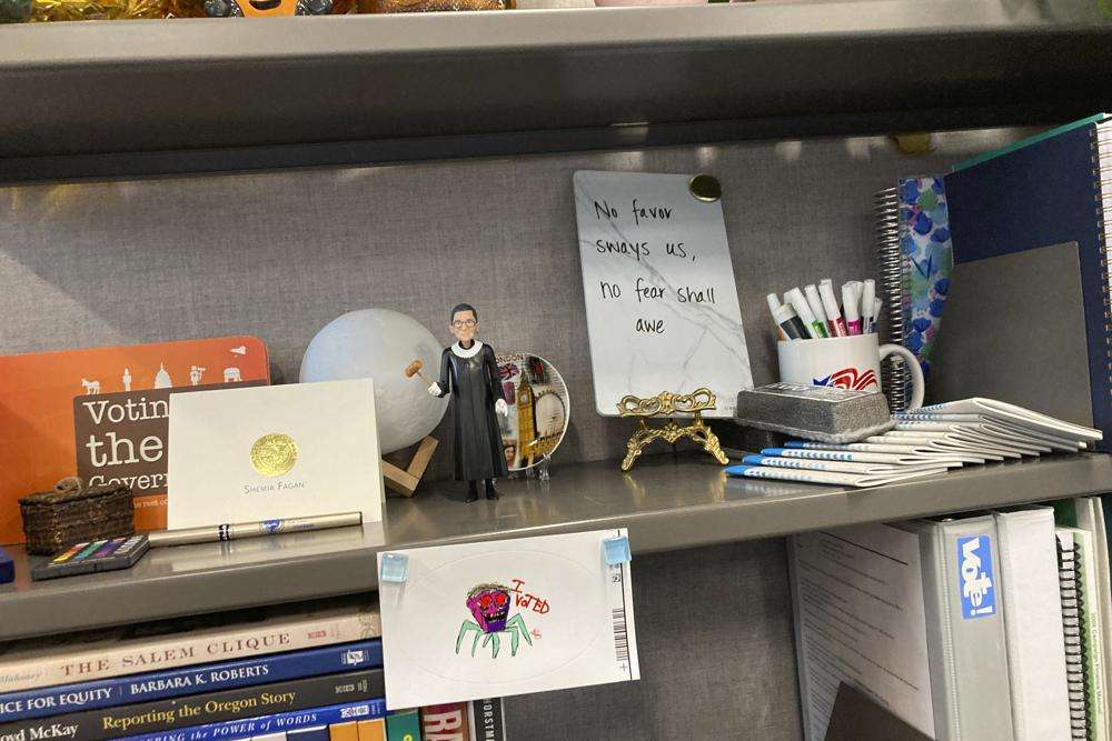 A bookshelf in the cubicle of Oregon elections investigator Alma Whalen displays an inspirational slogan that once adorned an Oregon newspaper: "No favor sways us, no fear shall awe," in Salem, Ore., on Oct. 17.