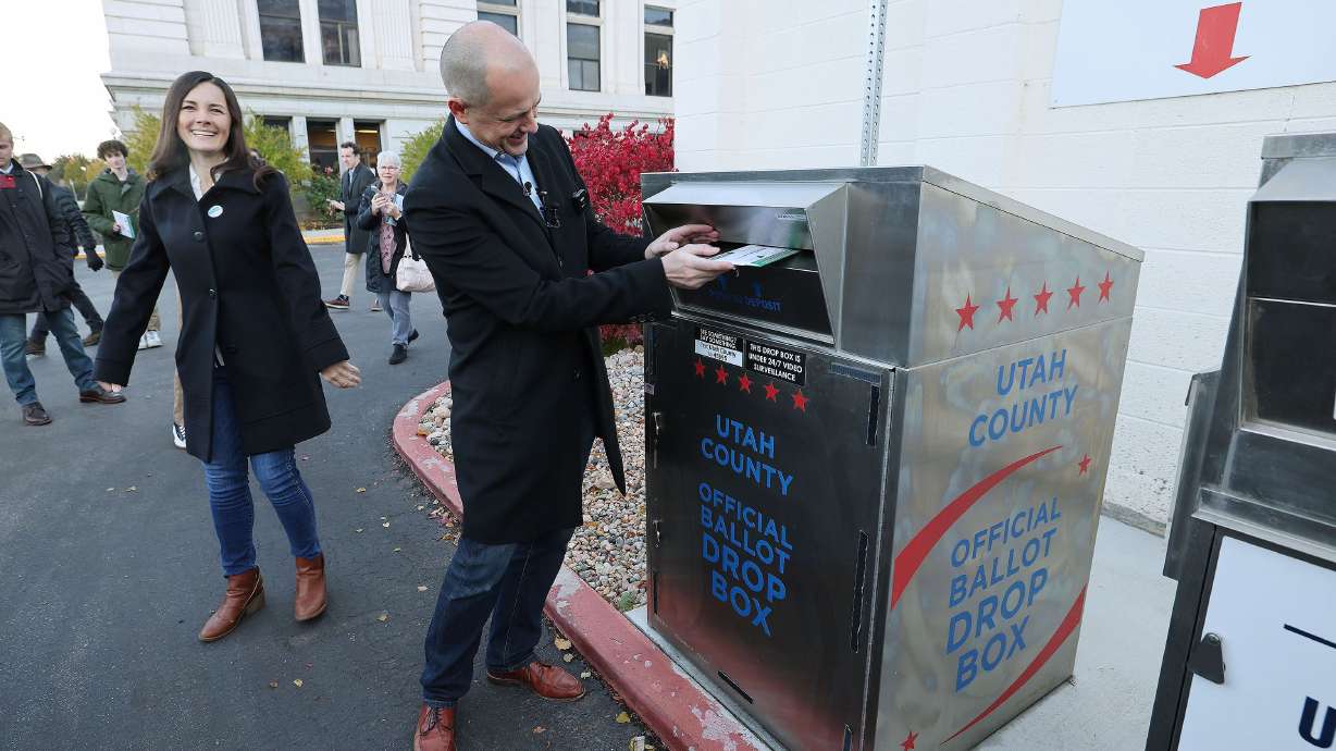 Emily McMullin, left, watches as her husband, Evan, drops off his ballot at a drop box in Provo on Friday. McMullin is running for U.S. Senate against GOP Sen. Mike Lee. Just days before Election Day, McMullin condemned comments Lee made about ending Social Security more than a decade ago.