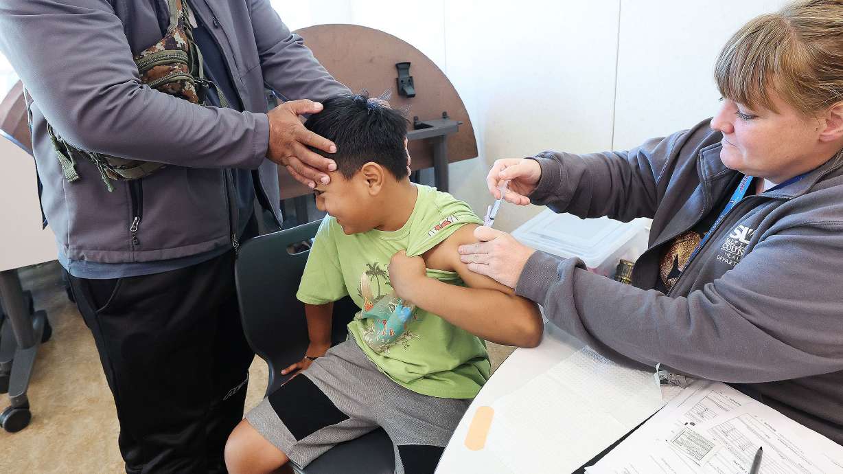 Steifi Otup holds his son Sitoshy Otup, 8, while he gets his flu vaccine at the Community Health Center Neighborhood Clinic in Salt Lake City on Oct. 28.