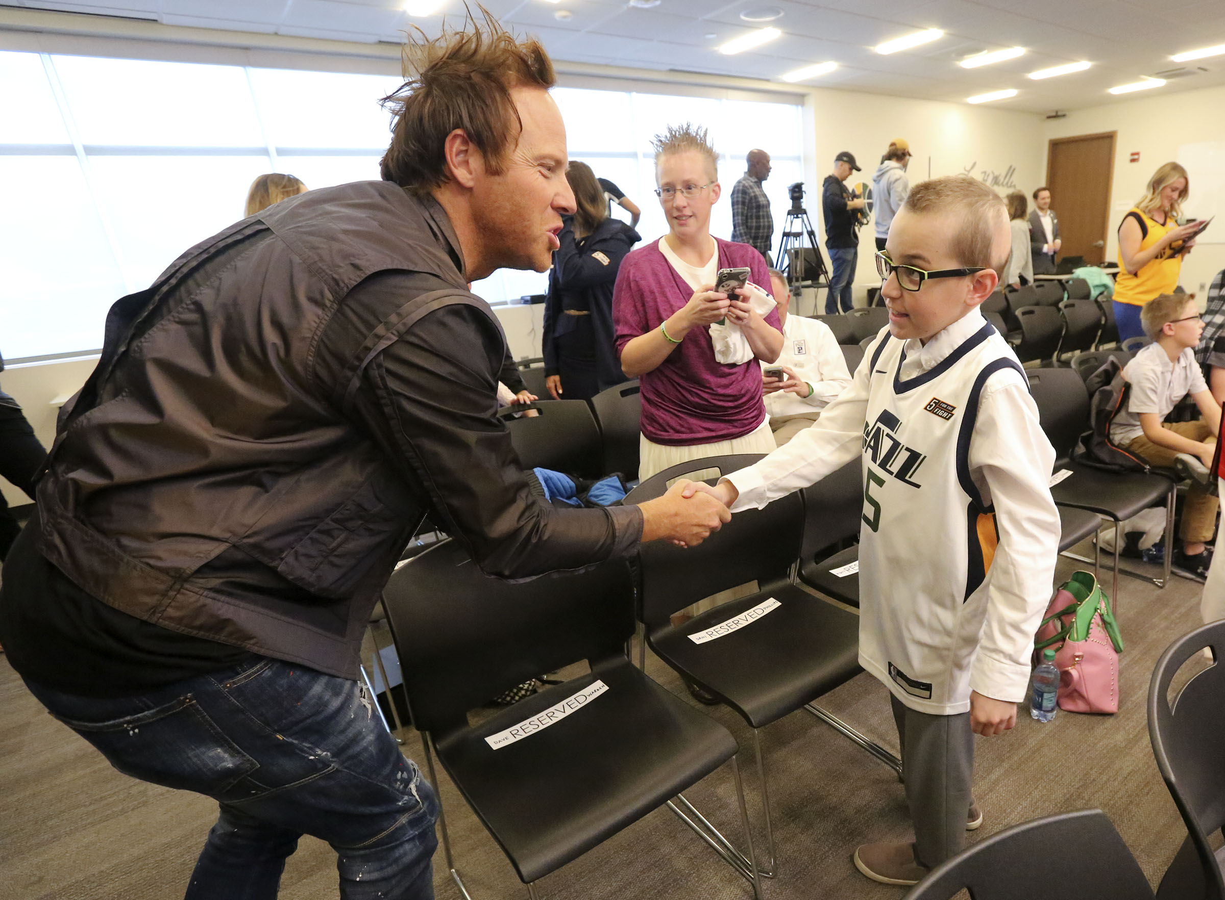 Ryan Smith, co-founder and CEO of Qualtrics and co-founder of 5 for the Fight, shakes hands with Wyatt Page, who fought brain cancer, during a press conference to announce that Qualtrics will sponsor the 5 for the Fight Utah Jazz jersey patch through the 2022-2023 season, at the Zions Bank Basketball Center in Salt Lake City on Oct. 21, 2019.