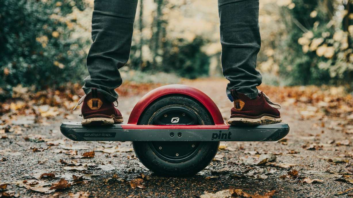 A man rides a Onewheel Pint, electric skateboard or hoverboard-type personal vehicle on a trail.